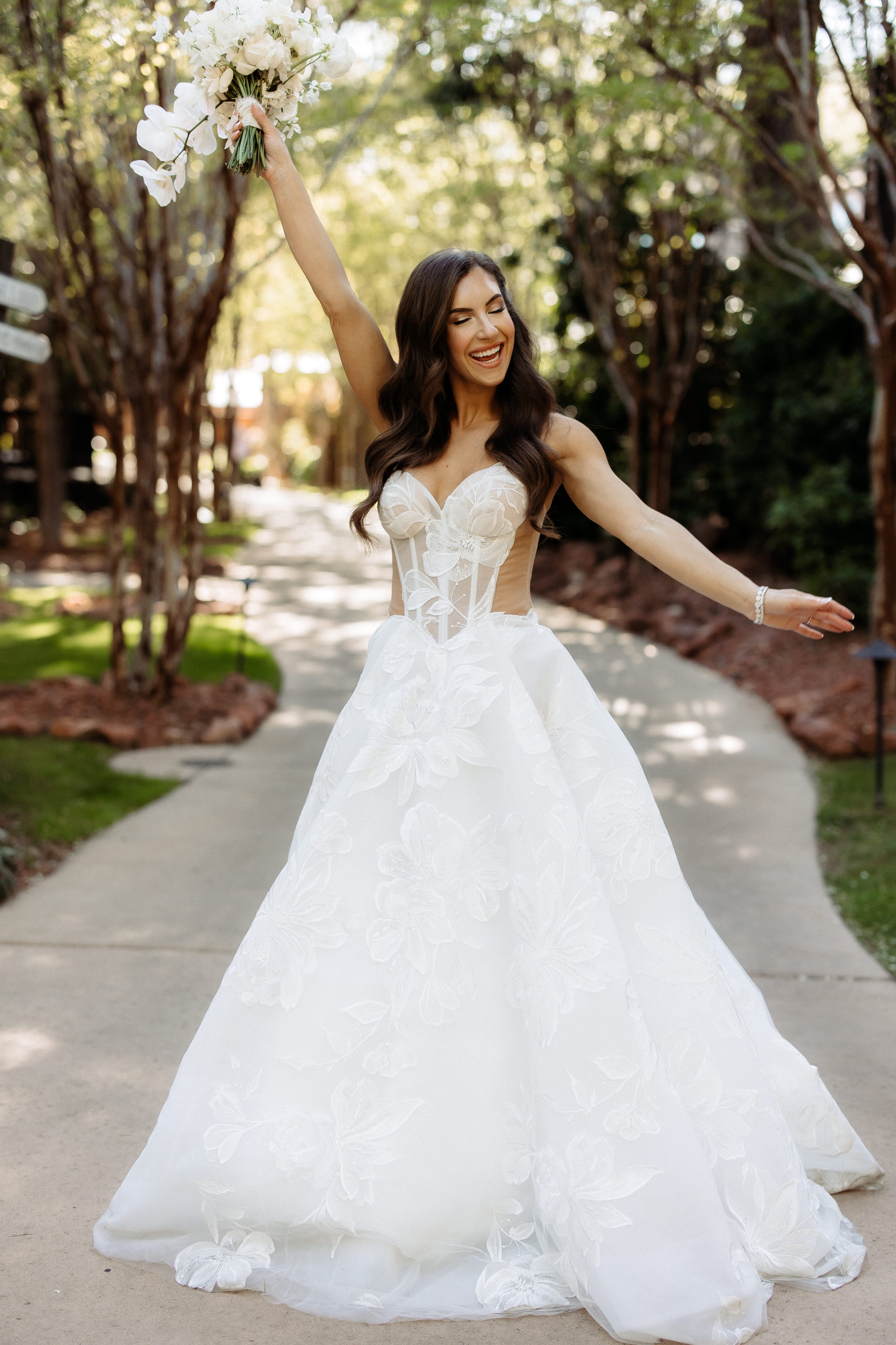 Woman in our Evelyn wedding dress holding a bouquet outdoors.