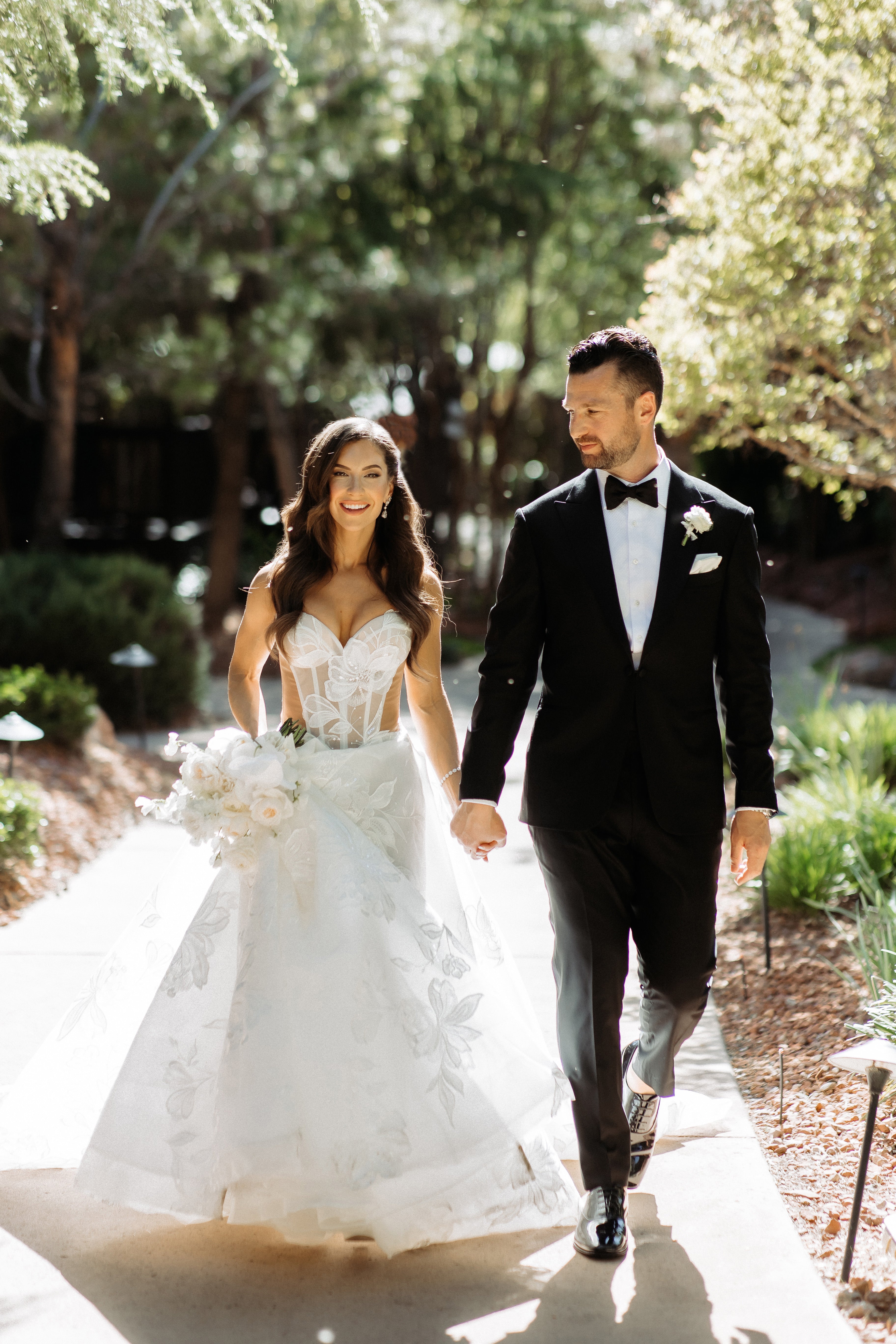 Man and woman wearing our Evelyn walking outdoors with greenery in the background