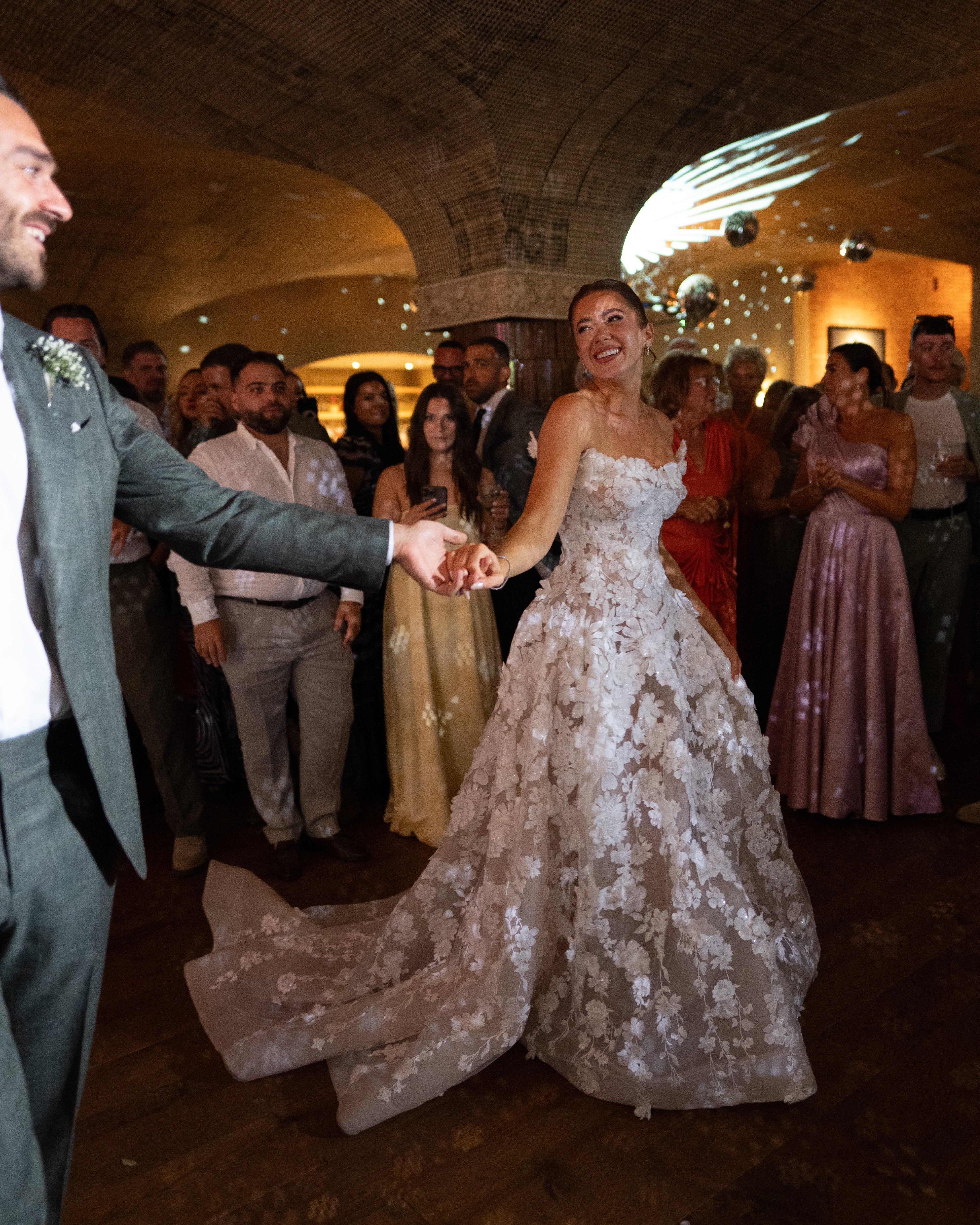 GL Bride Emily in our Rosemary and husband dancing at a wedding reception with guests in the background.