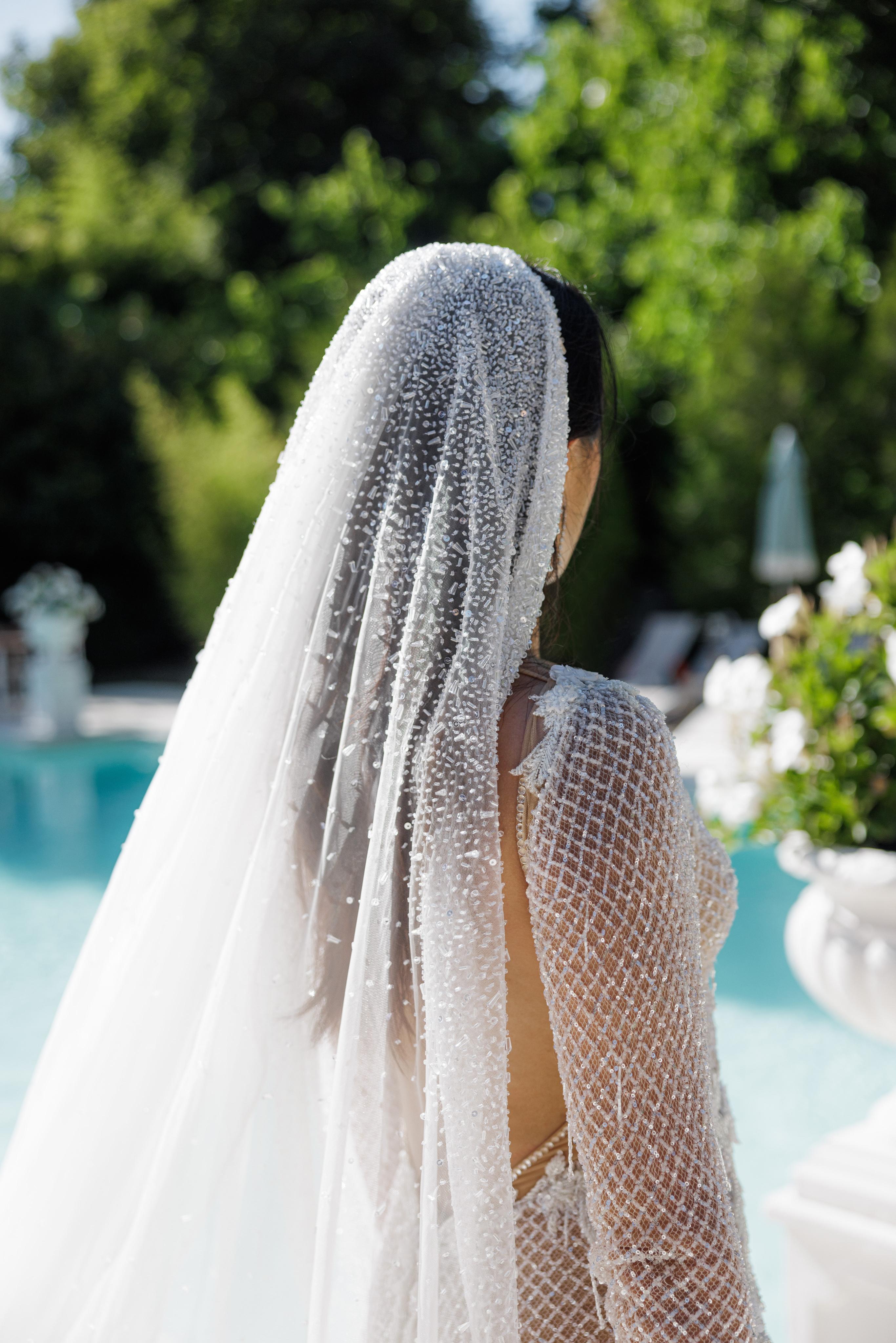 Person wearing a long white veil with a blurred outdoor background