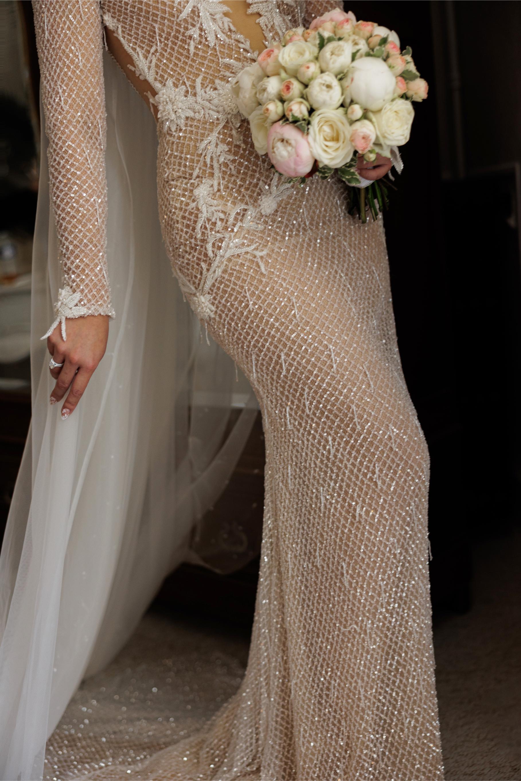 Bride in a beaded wedding gown holding a bouquet of flowers.