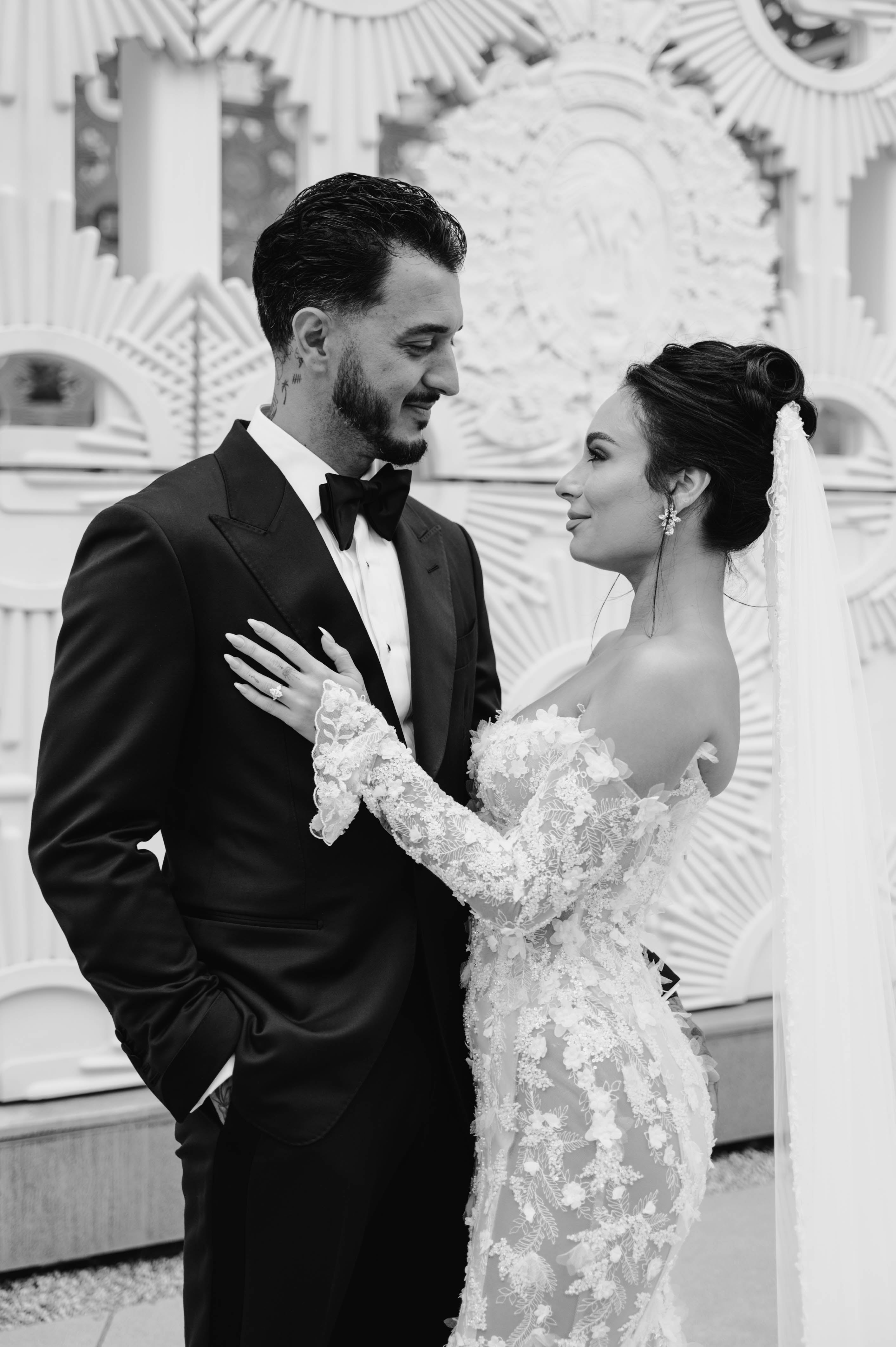Black and white photo of GL Bride Eva and her husband in formal attire with decorative background