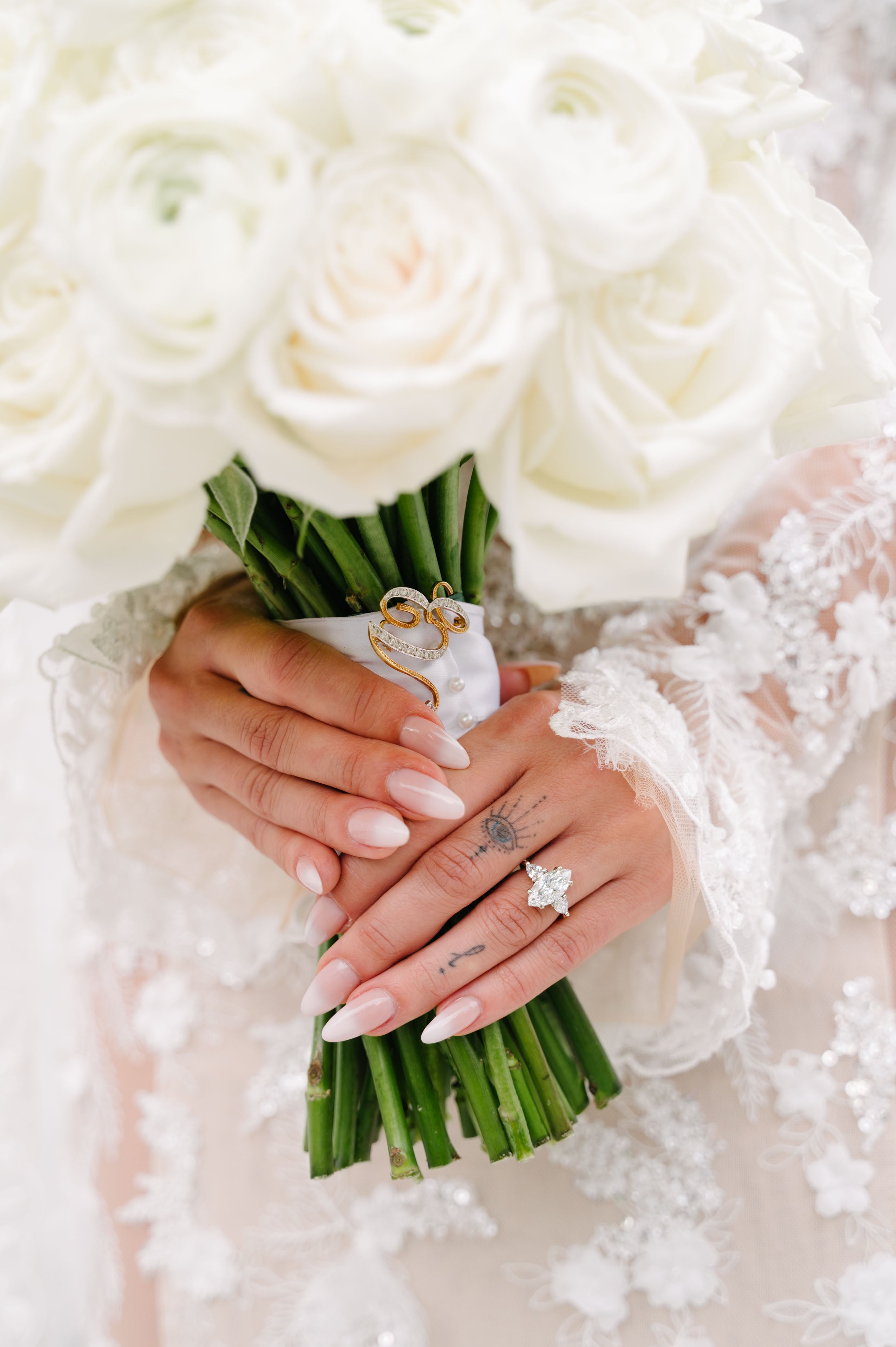 GL Bride Eva hands holding a bouquet of white roses with a ring on one finger.