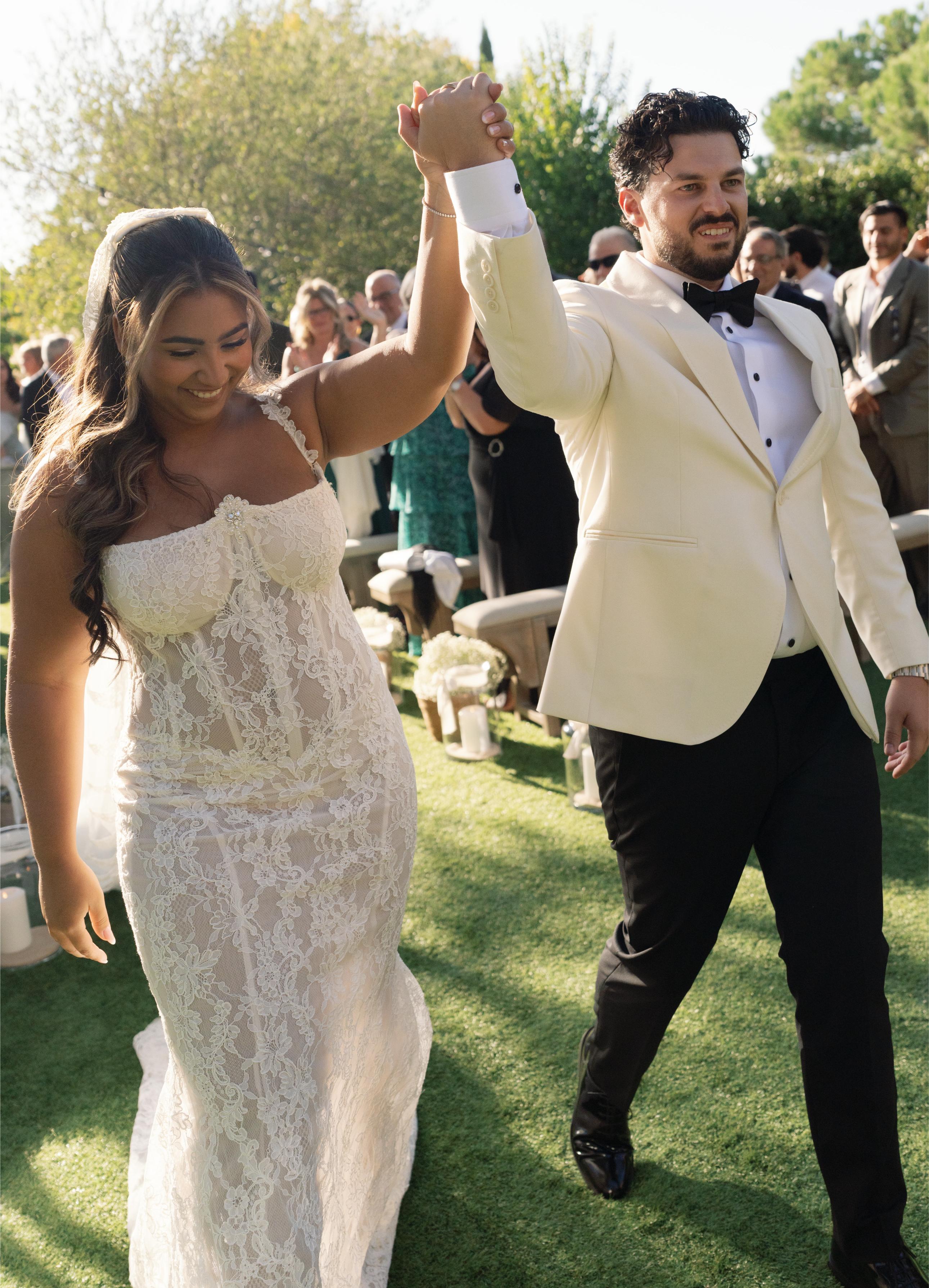 GL Bride Janai in our Anais  and husband in formal attire celebrating outdoors on a sunny day.