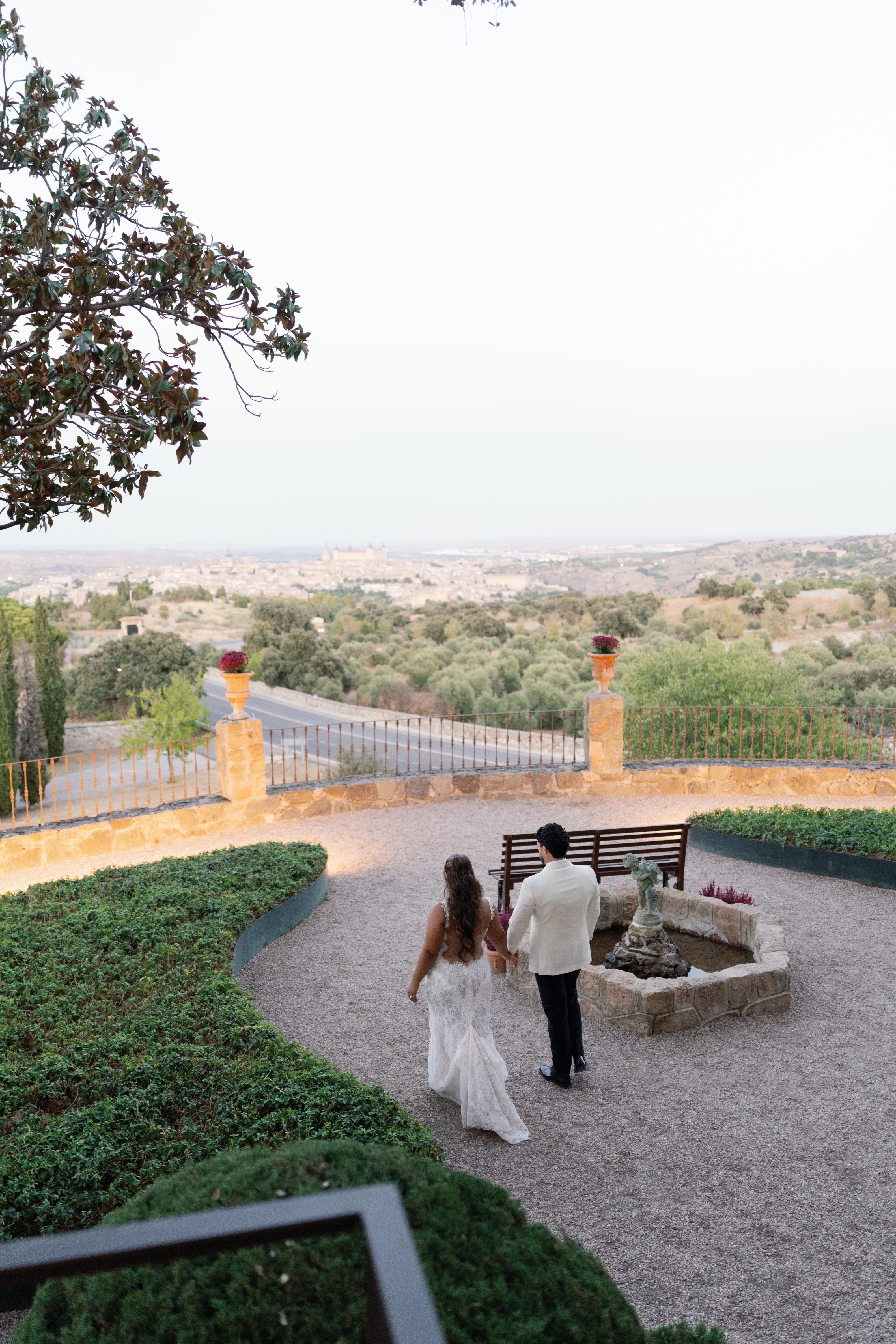 GL Bride Janai in our Anais and her husband walking in a garden with a scenic view in the background