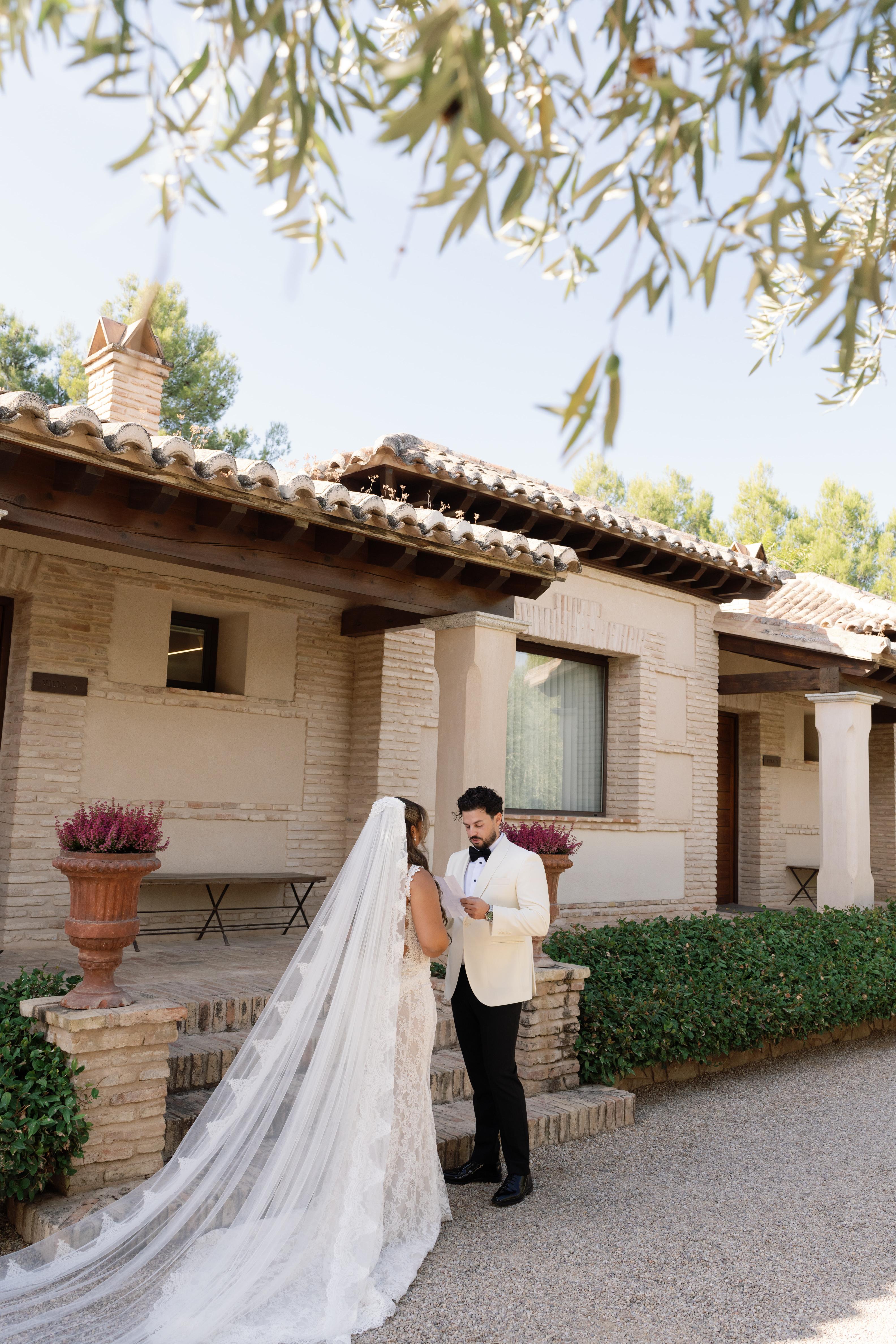 GL Bride Janai in our Anais and her husband standing in front of a house with greenery
