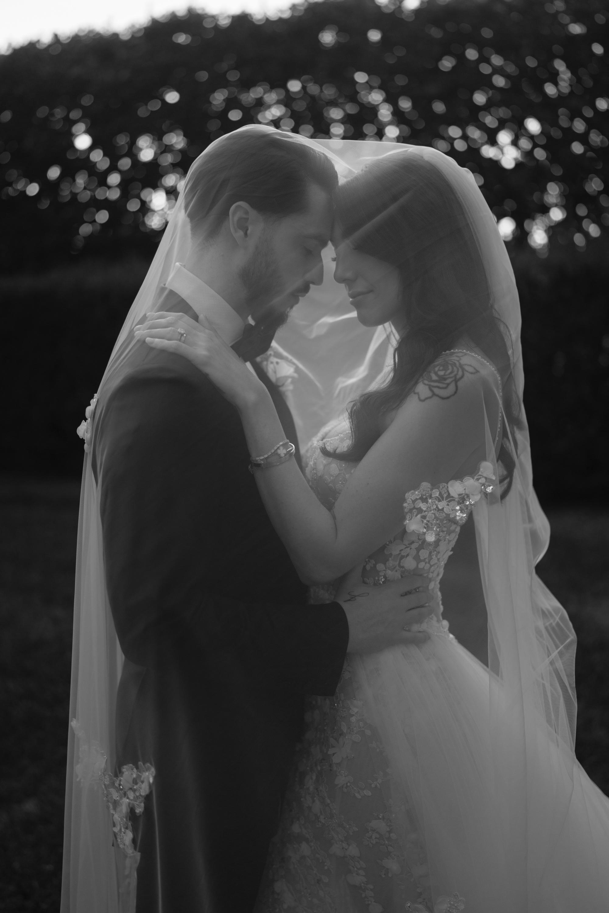 Black and white photo of our GL Bride Jessica wearing our Catalina gown  embracing outdoors.