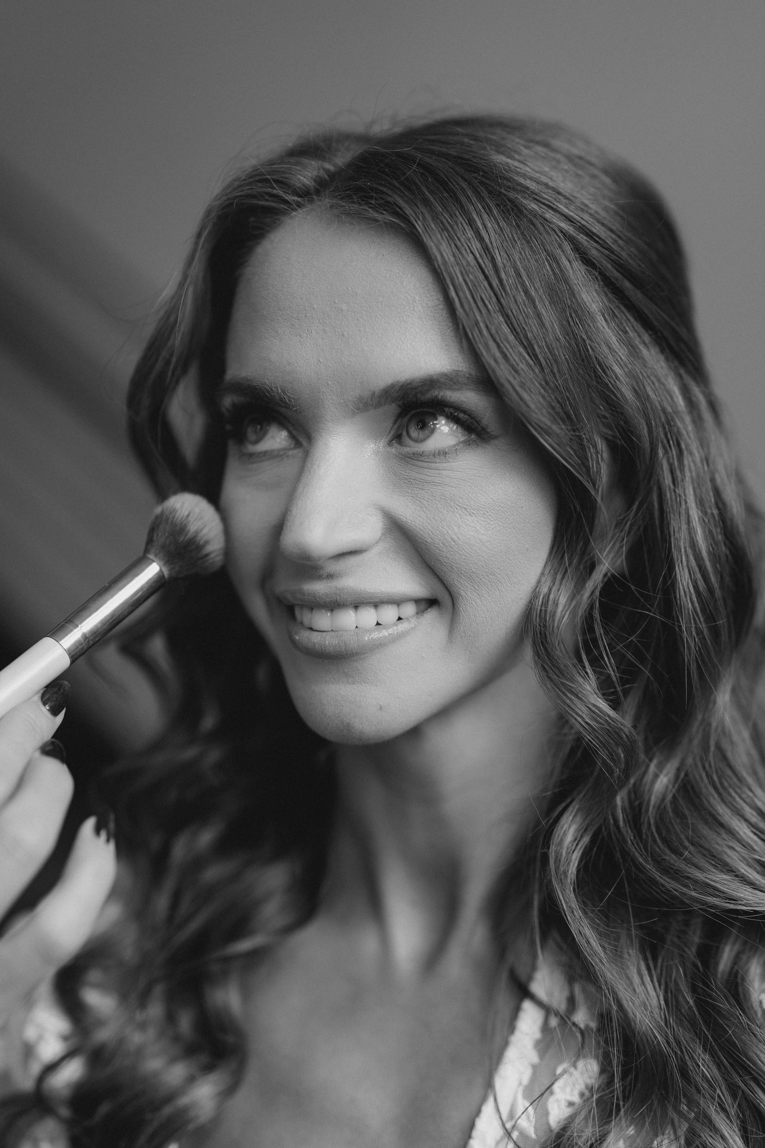 Black and white photo of a woman with makeup brush