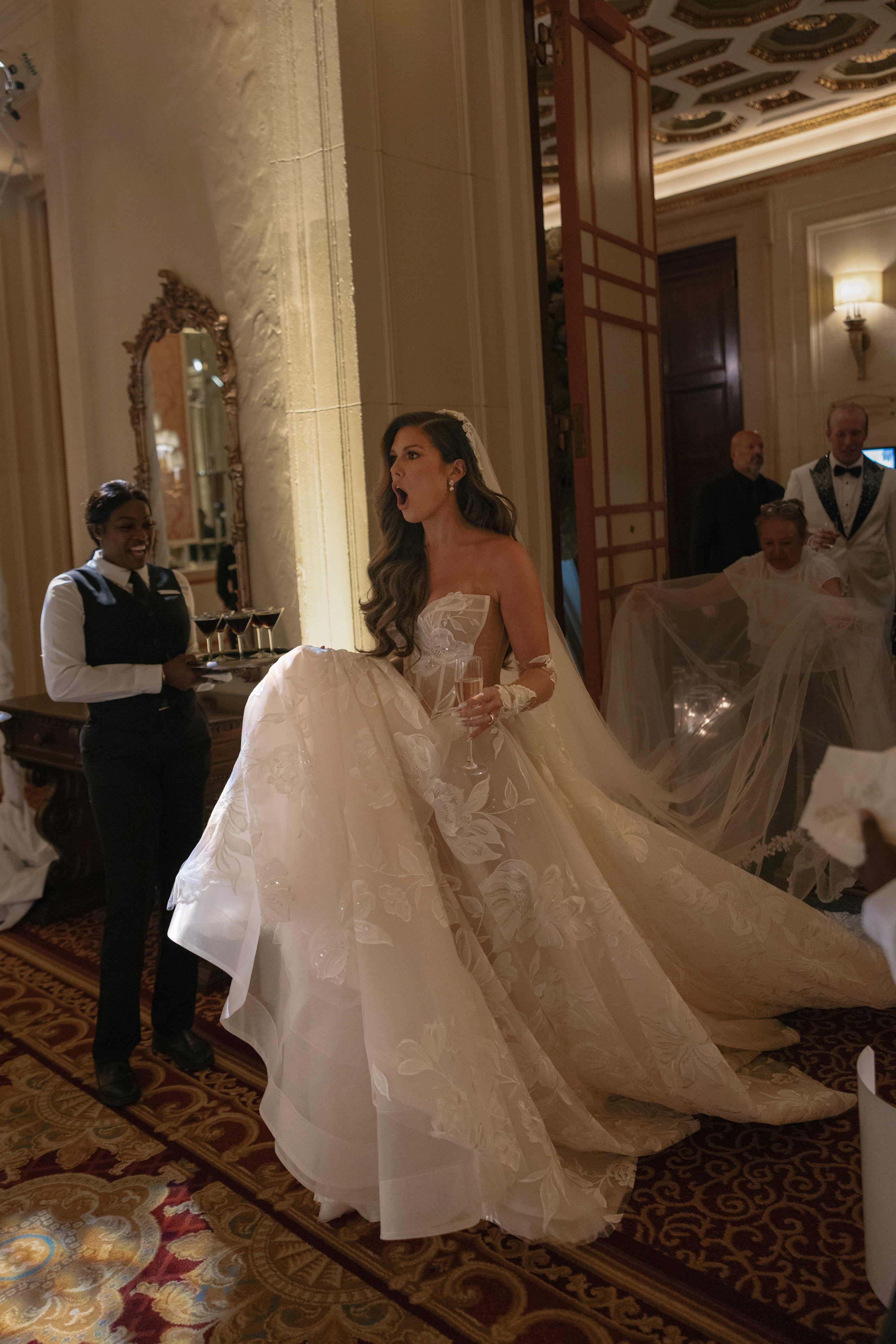 Woman in a wedding dress standing in an elegant room with decorative elements.