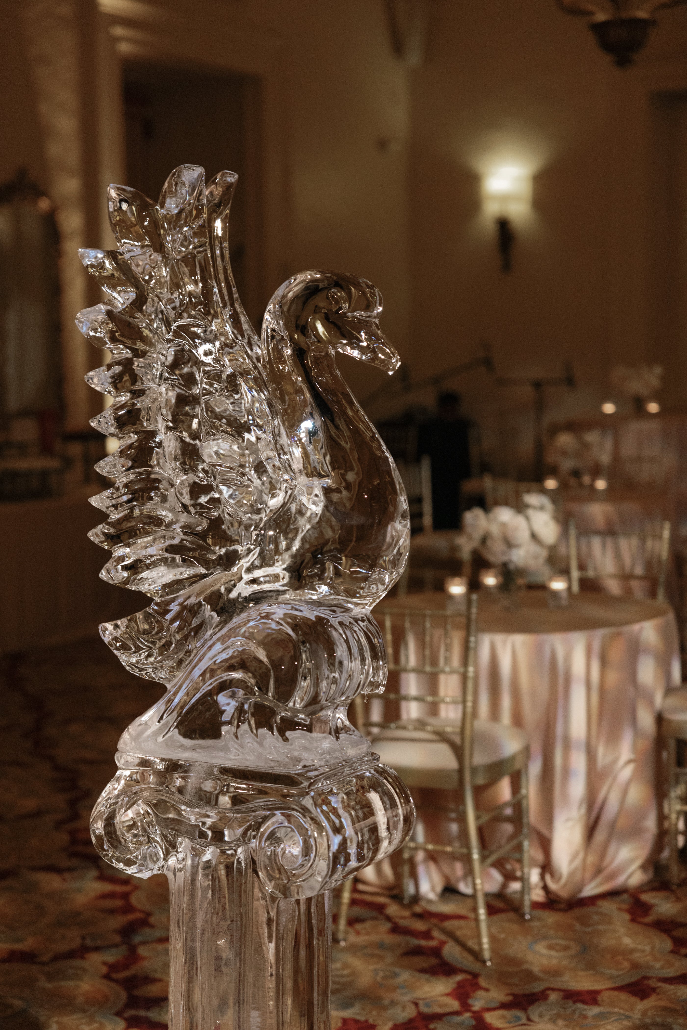 Crystal swan sculpture in a formal event setting with table and chairs.