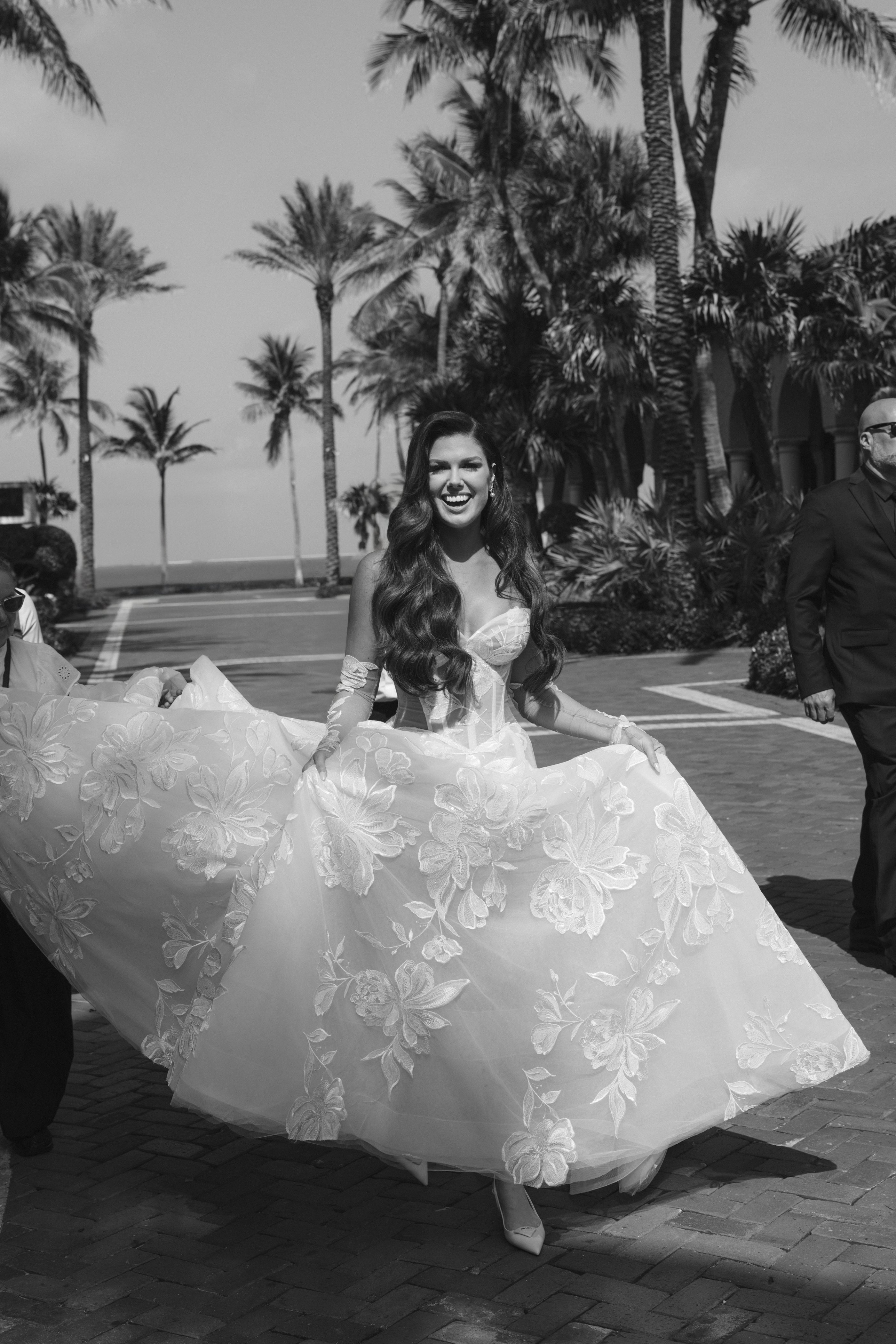 Woman in a white floral dress standing outdoors with palm trees in the background
