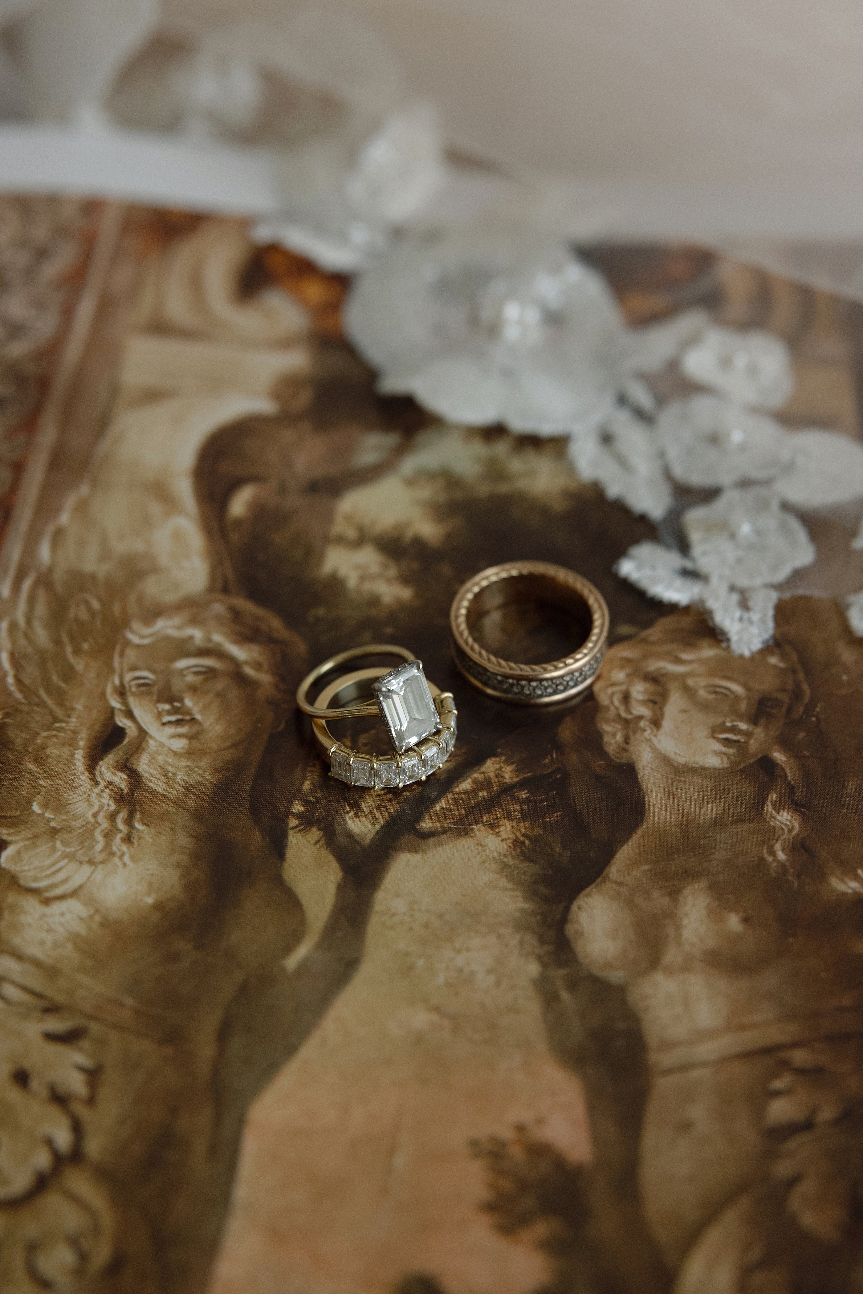 Two rings on a decorative surface with classical sculptures and flowers.