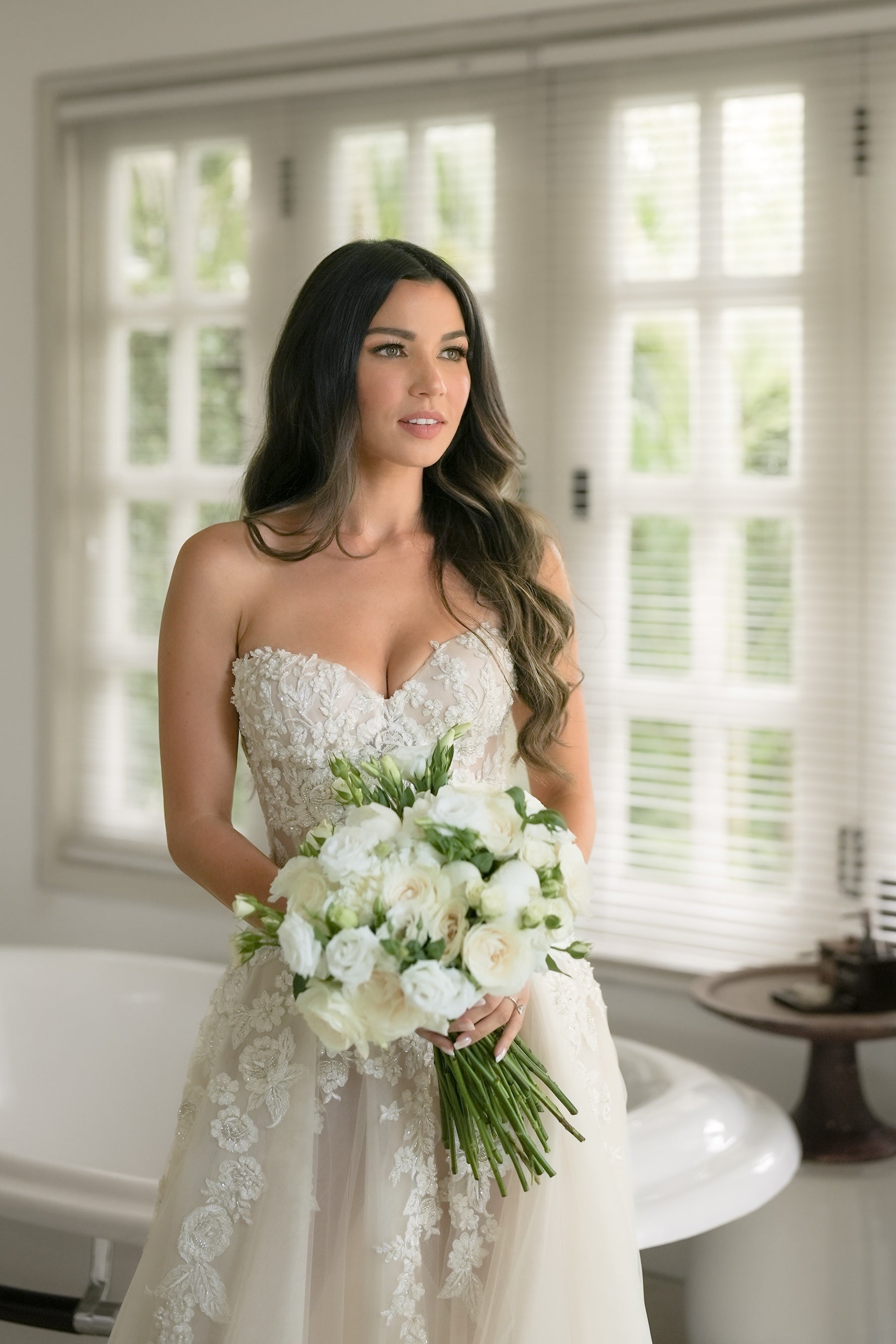 Woman in a wedding dress holding a bouquet of flowers indoors.