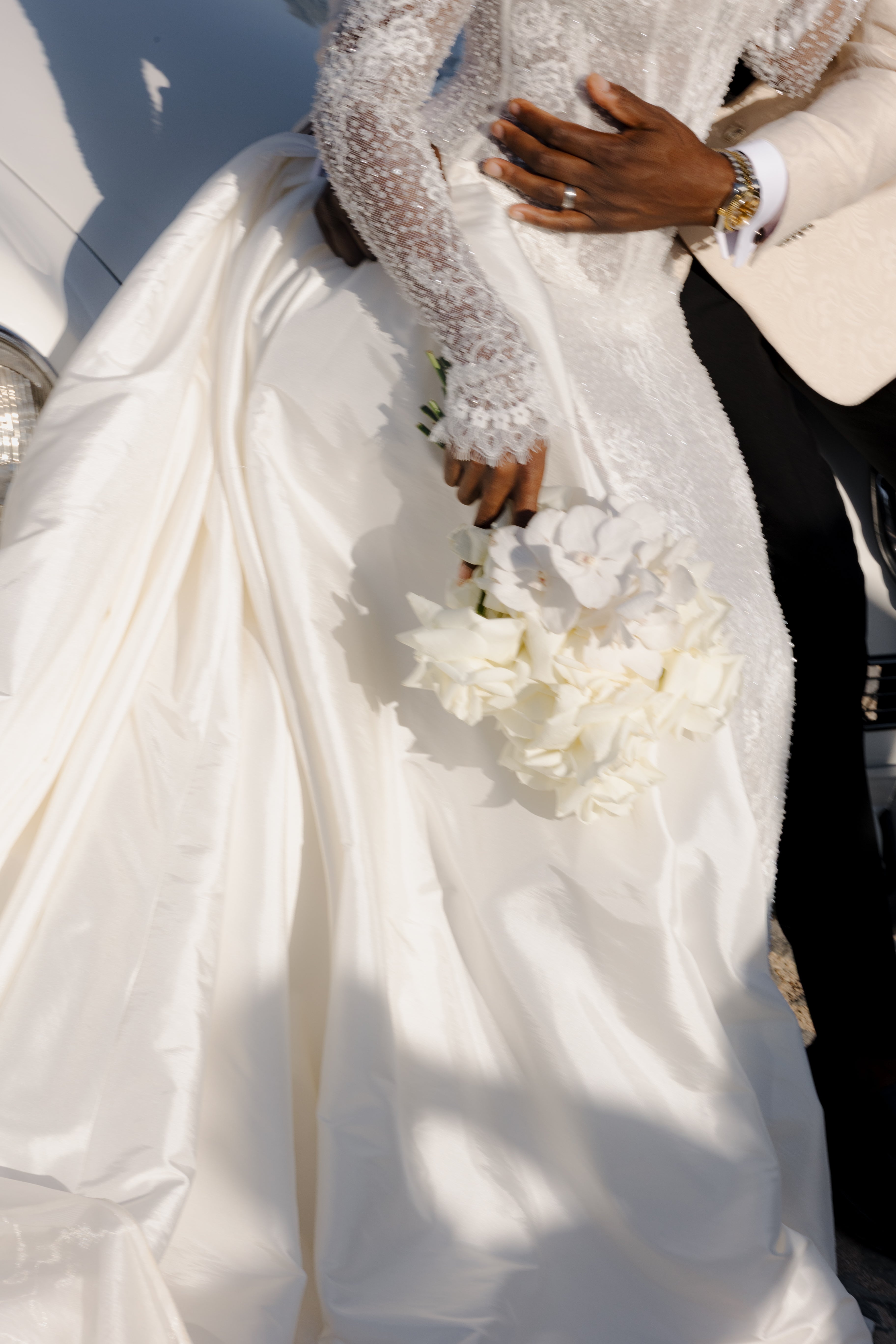 Person in a white wedding dress holding a bouquet with a blurred background