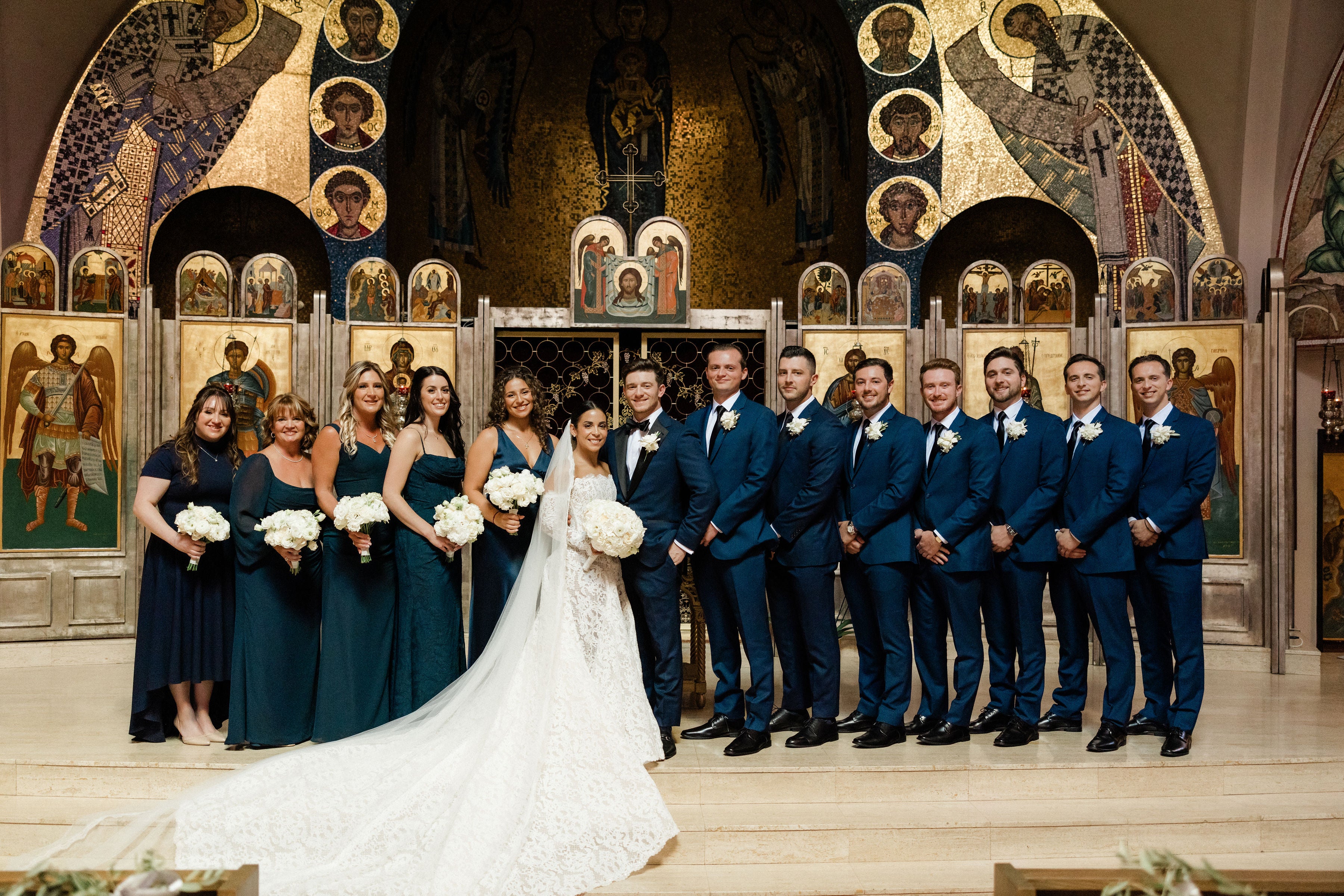 Wedding party posing in a church with decorative arches and icons.