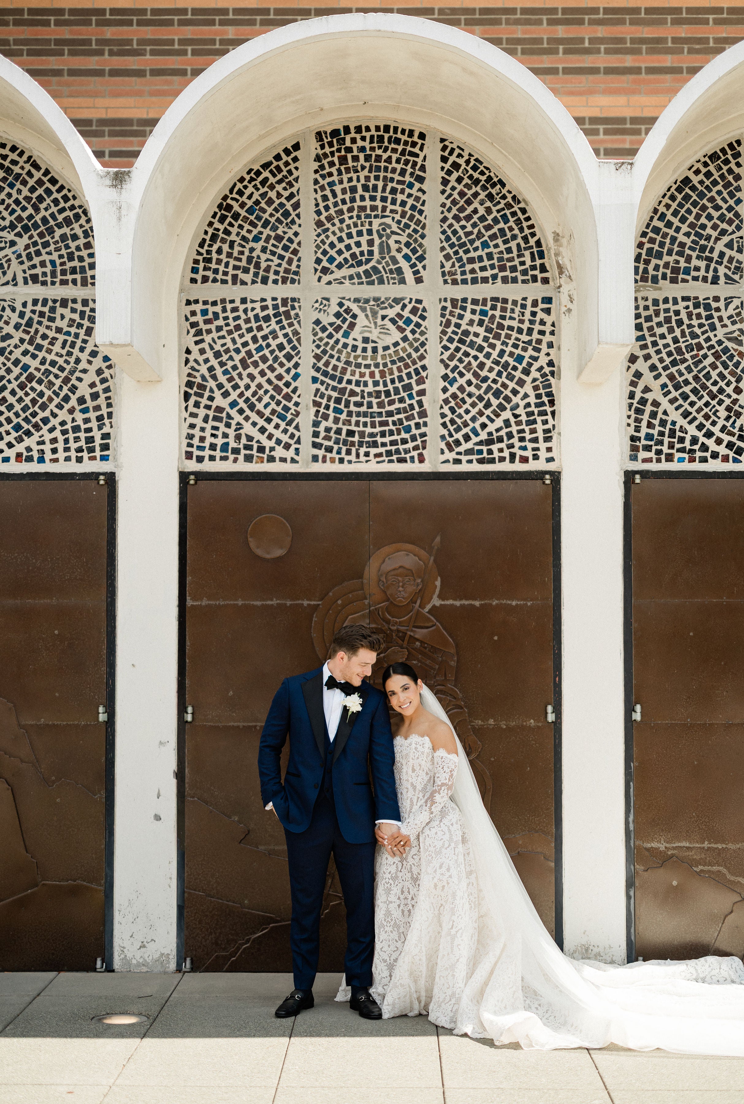 GL Bride Megan wearing Galia Lahav Splendid standing in front of a decorative wall with arches.