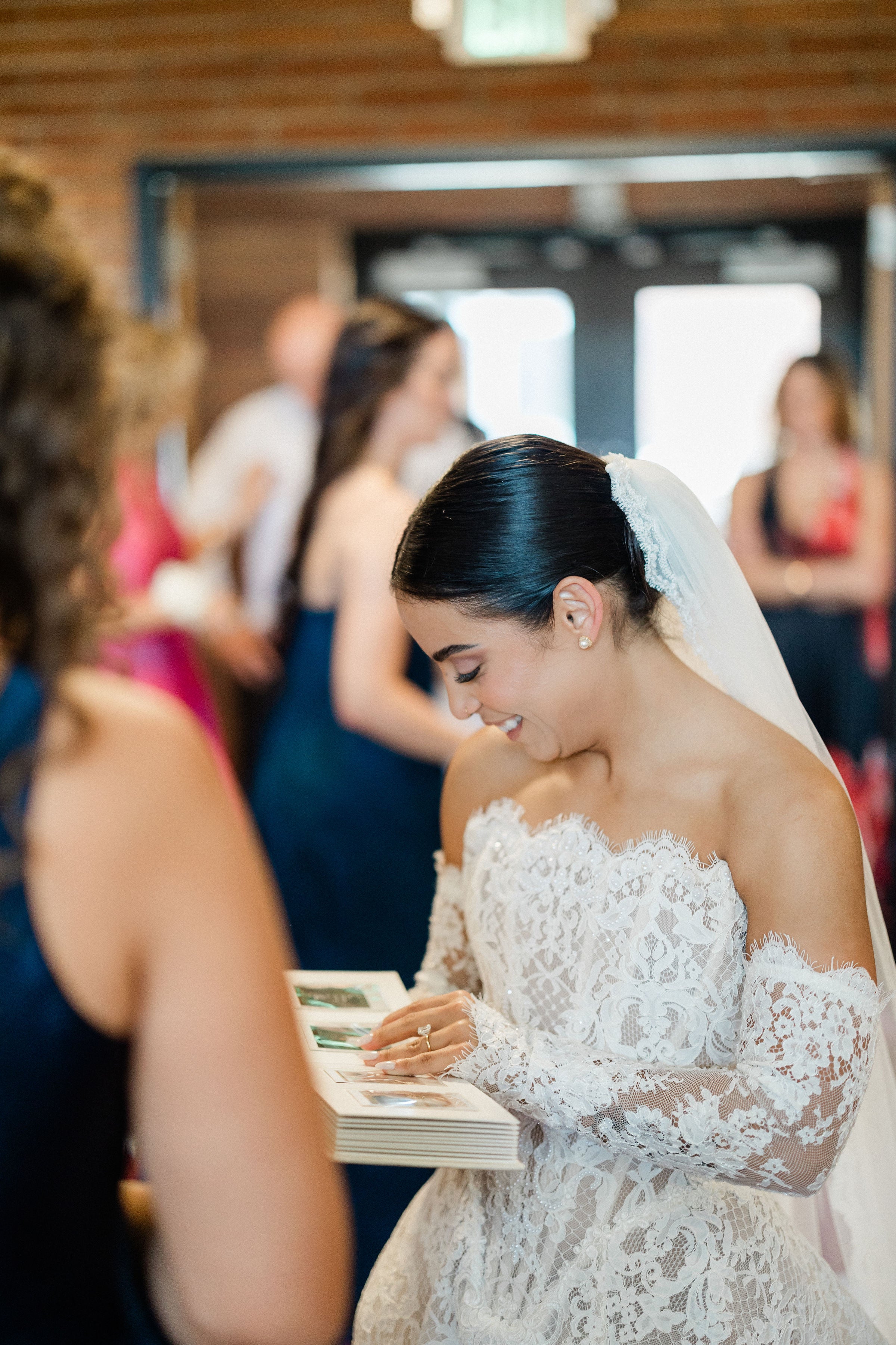GL Bride Megan in the white lace Splendid gown by Galia Lahav with a veil, surrounded by people in a social setting.