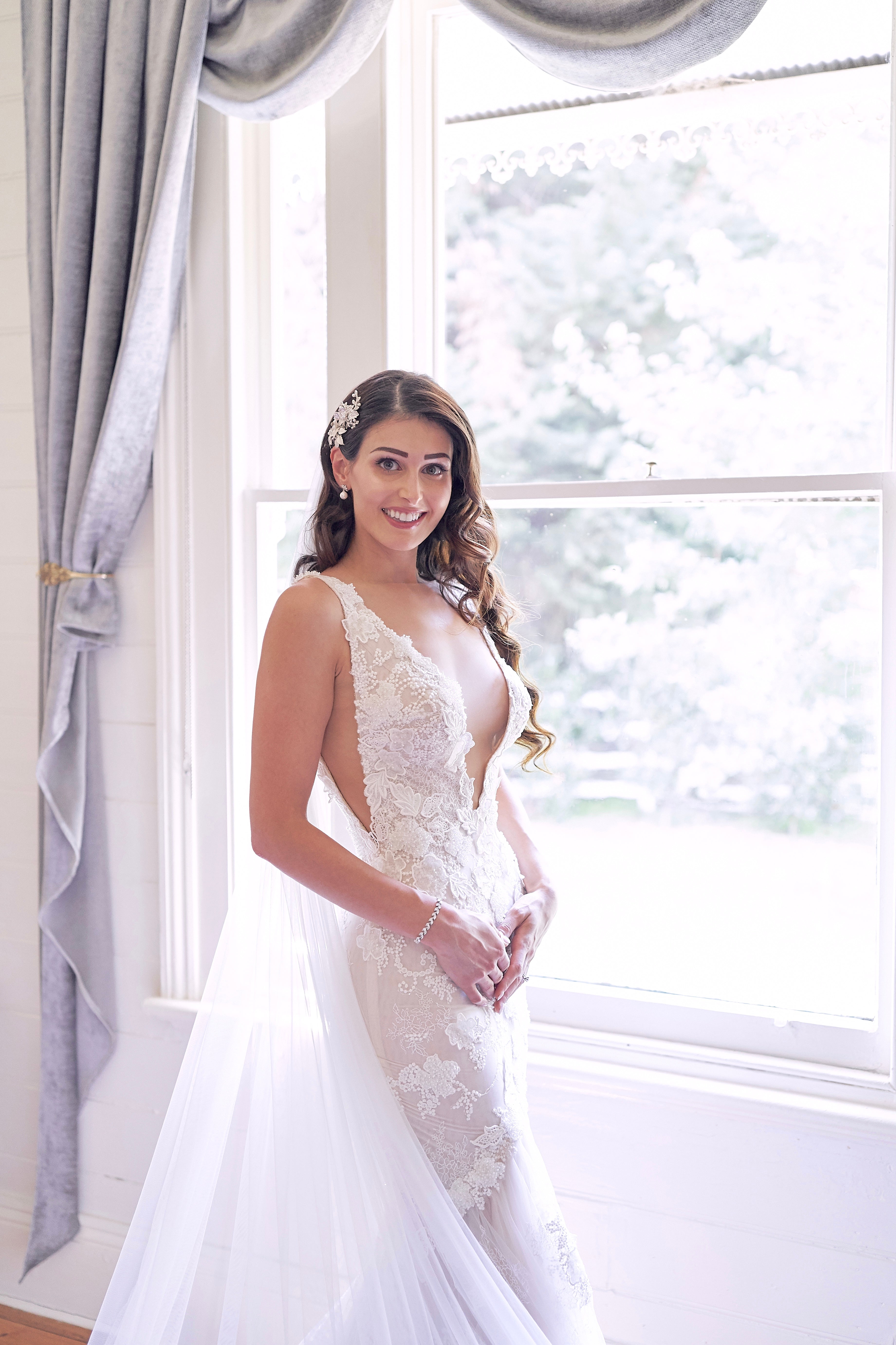 GL Bride Nadia in our GALA 1001 dress standing by a window with light streaming in.