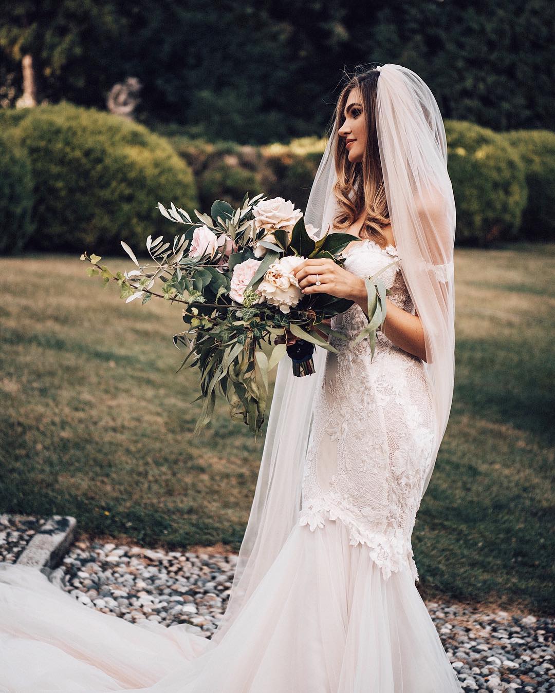 GL Bride Natalie in our Tony gown in the garden holding her floral bouquet 