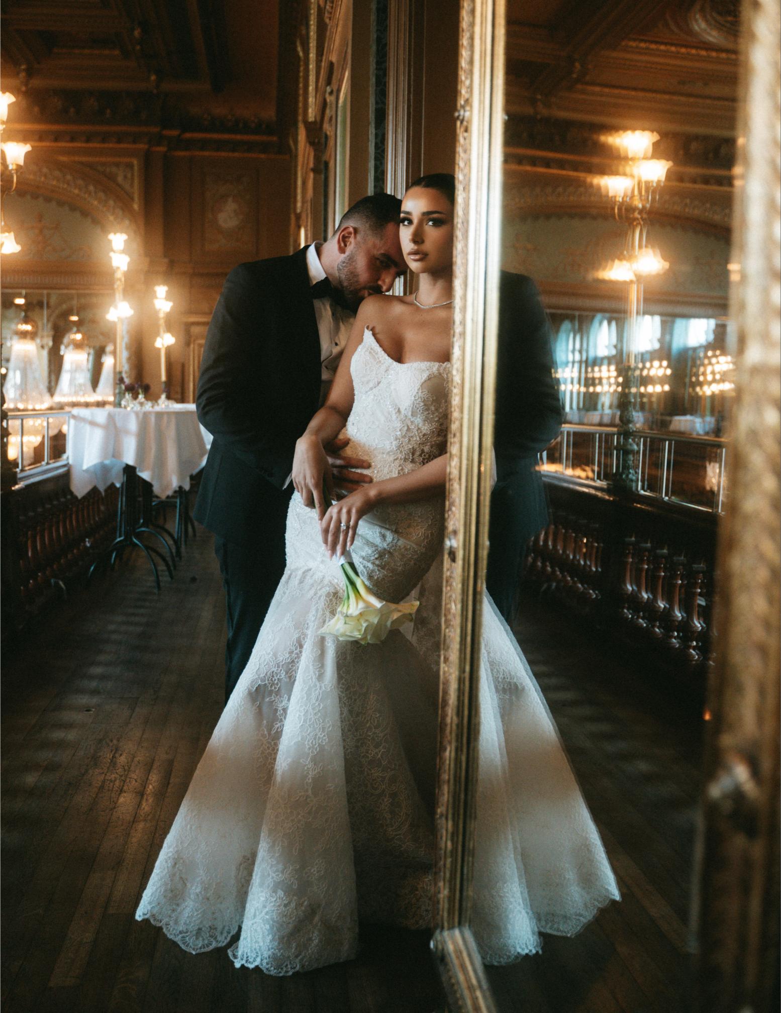 GL Bride in the Scarlett and her groom embracing in a grand room with ornate decor