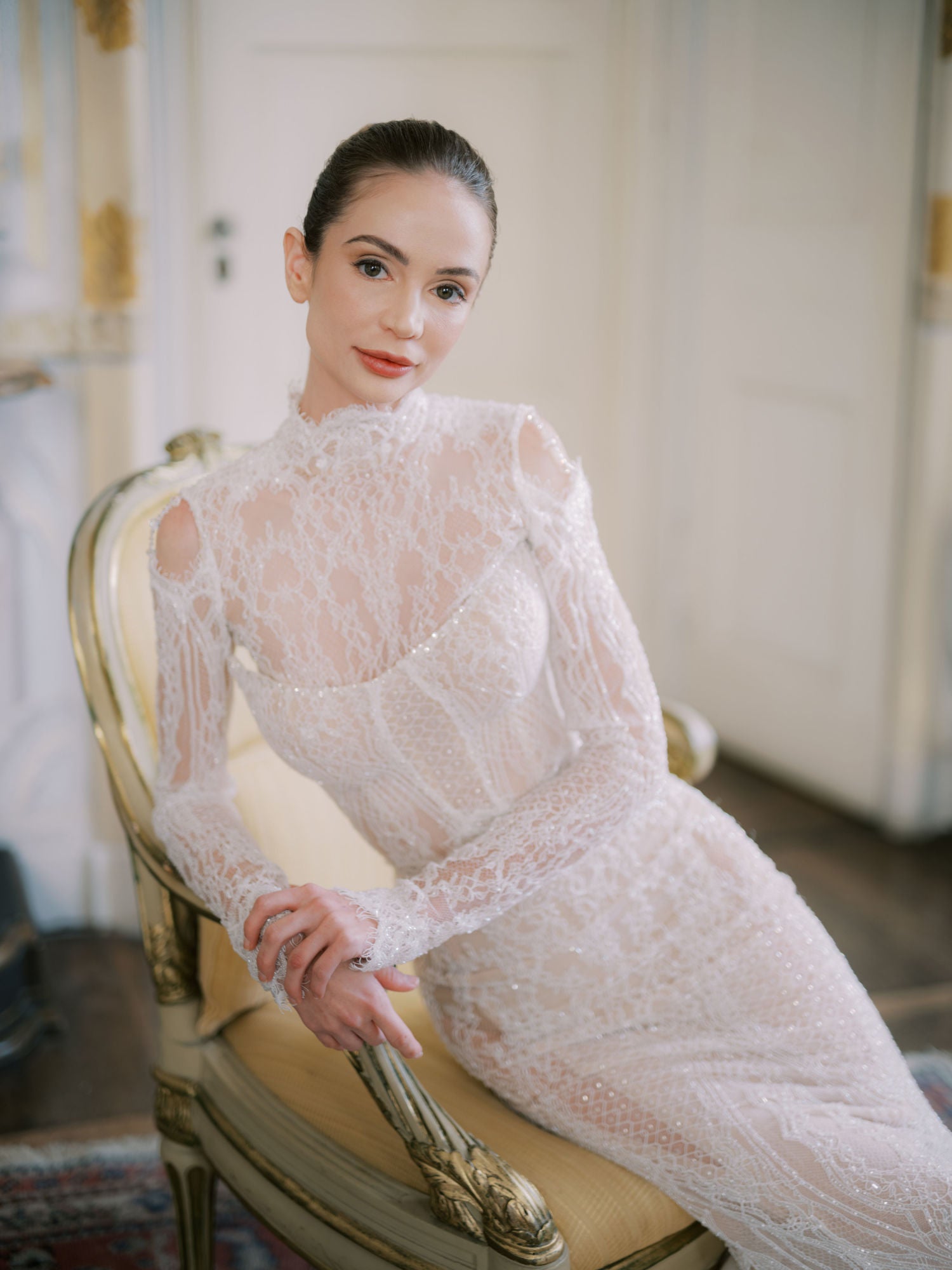 GL Bride Sarah Ingle in Galia Lahav's Élysée sitting on an ornate chair.