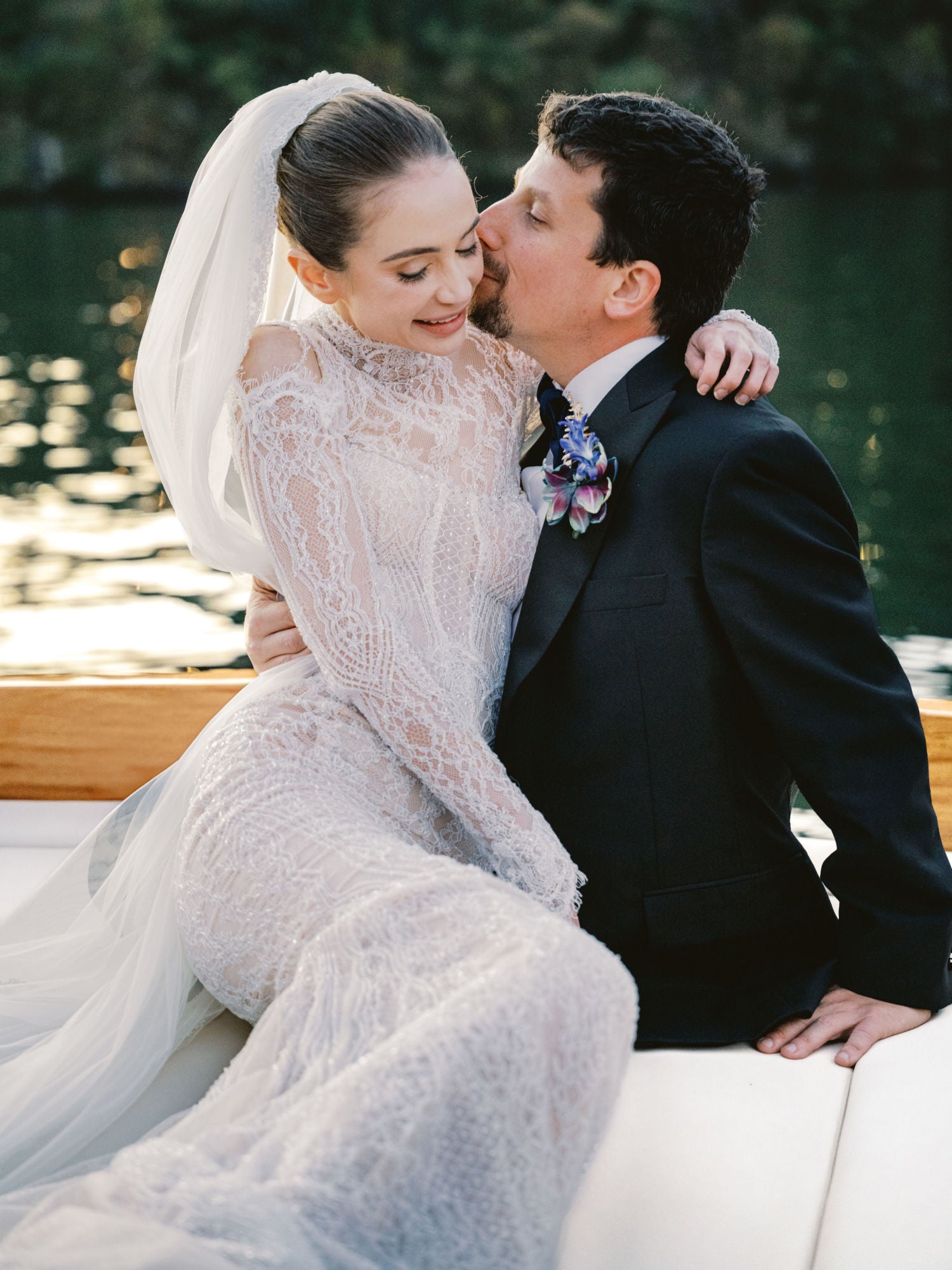 Groom kissing our GL Bride Sarah Ingle in our Élysée by a body of water.