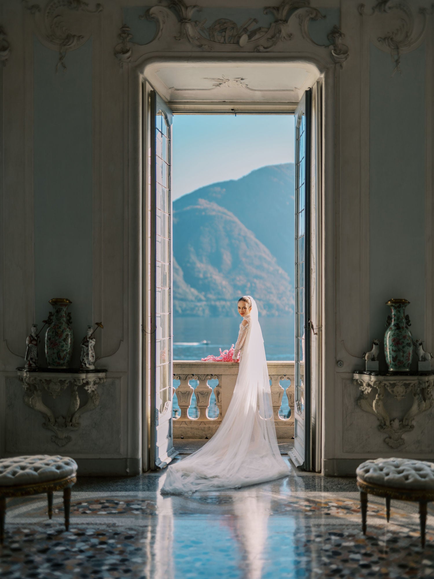 GL Bride Sarah Ingle in our Élysée standing in an elegant room with a mountain view.