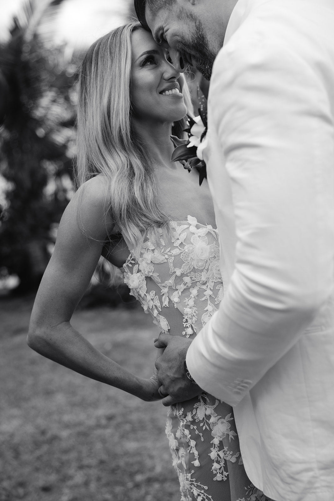 Black and white photo of a couple embracing outdoors. Bride Summer wearing Veronica gown by Galia Lahav