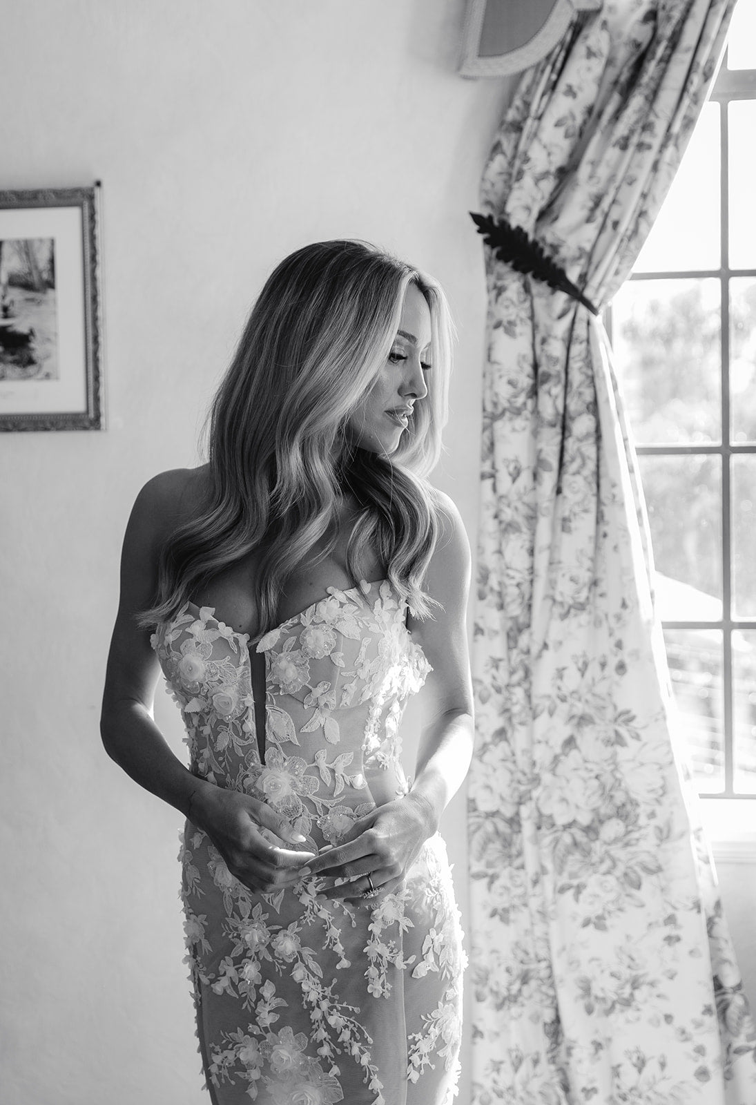 GL Bride Summer Fox in the lace Veronica dress by Galia Lahav standing in a room with floral curtains. 