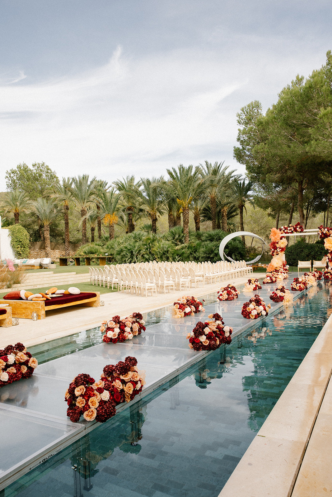 Decorative flower arrangements in a pool with a wedding setup in the background
