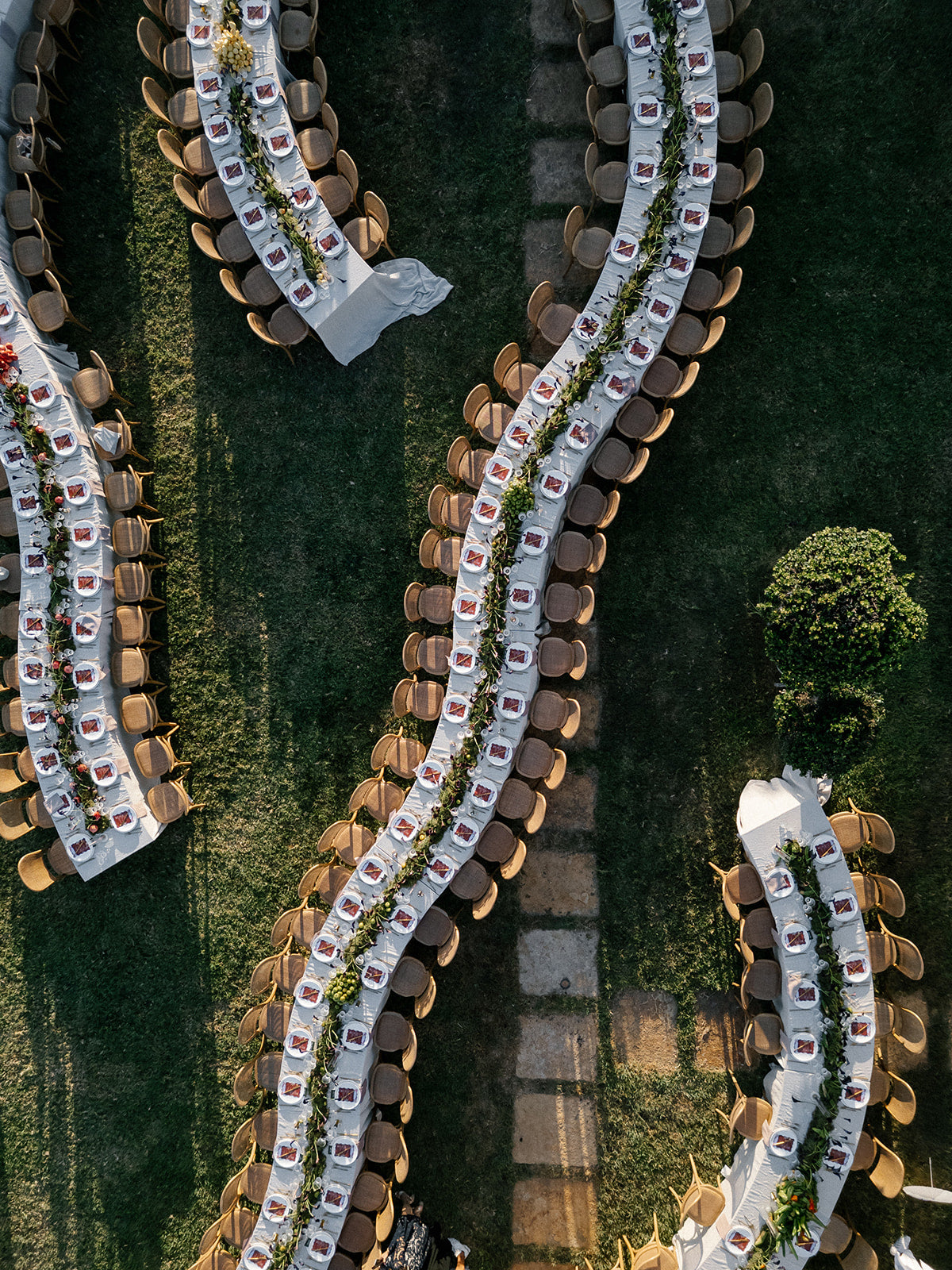 Aerial view of a formal event setup with tables and chairs in a garden.