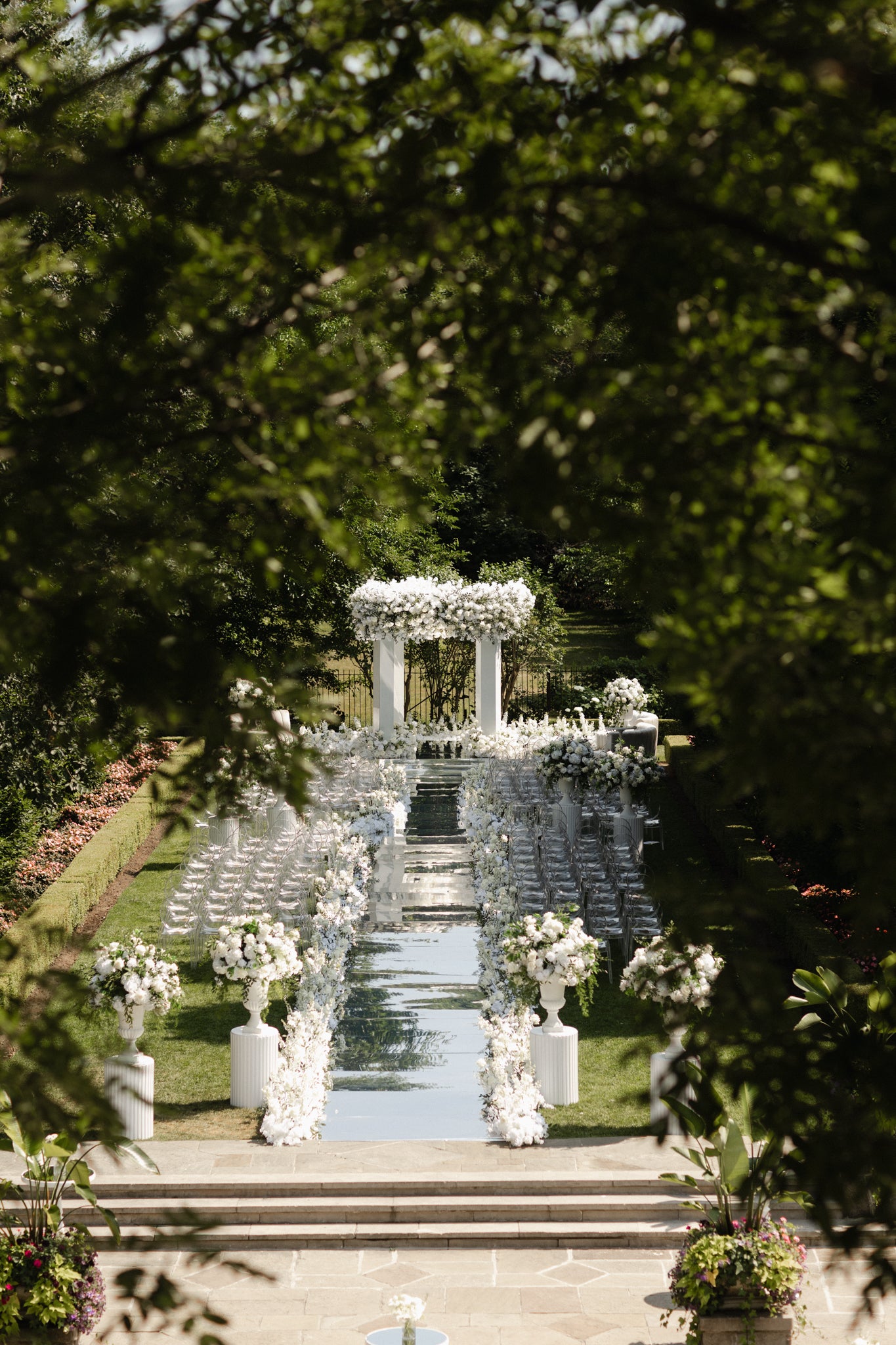 Decorative setup with floral arrangements and a white archway in a garden setting