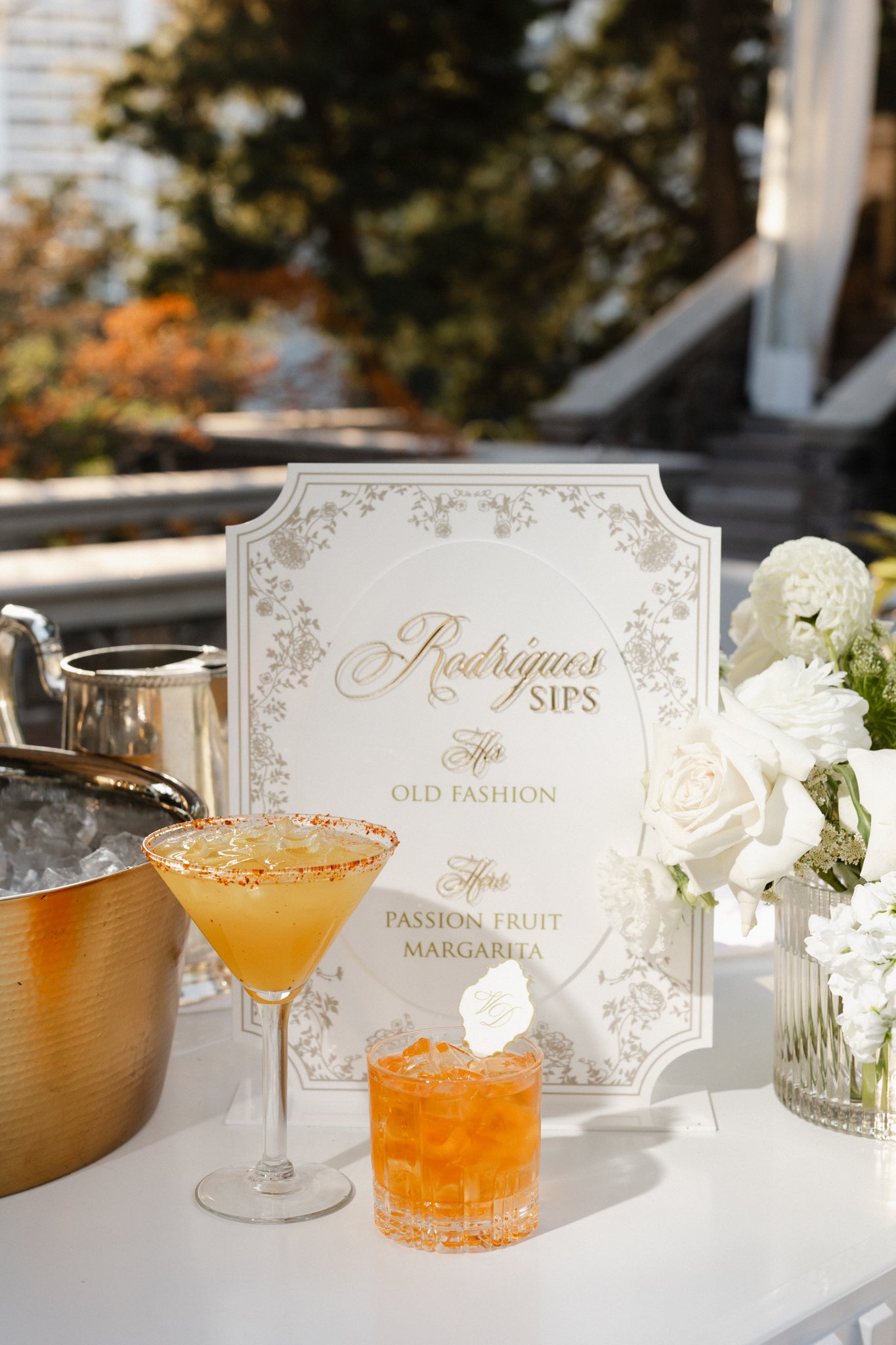 Two cocktails on a table with a decorative sign in the background