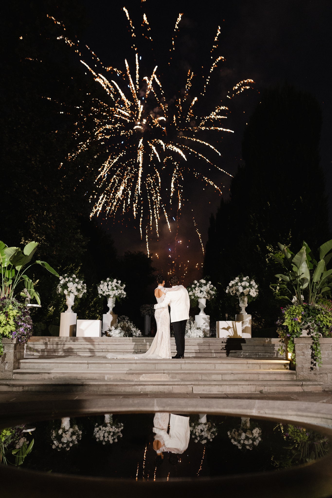 Couple standing on steps with fireworks in the background