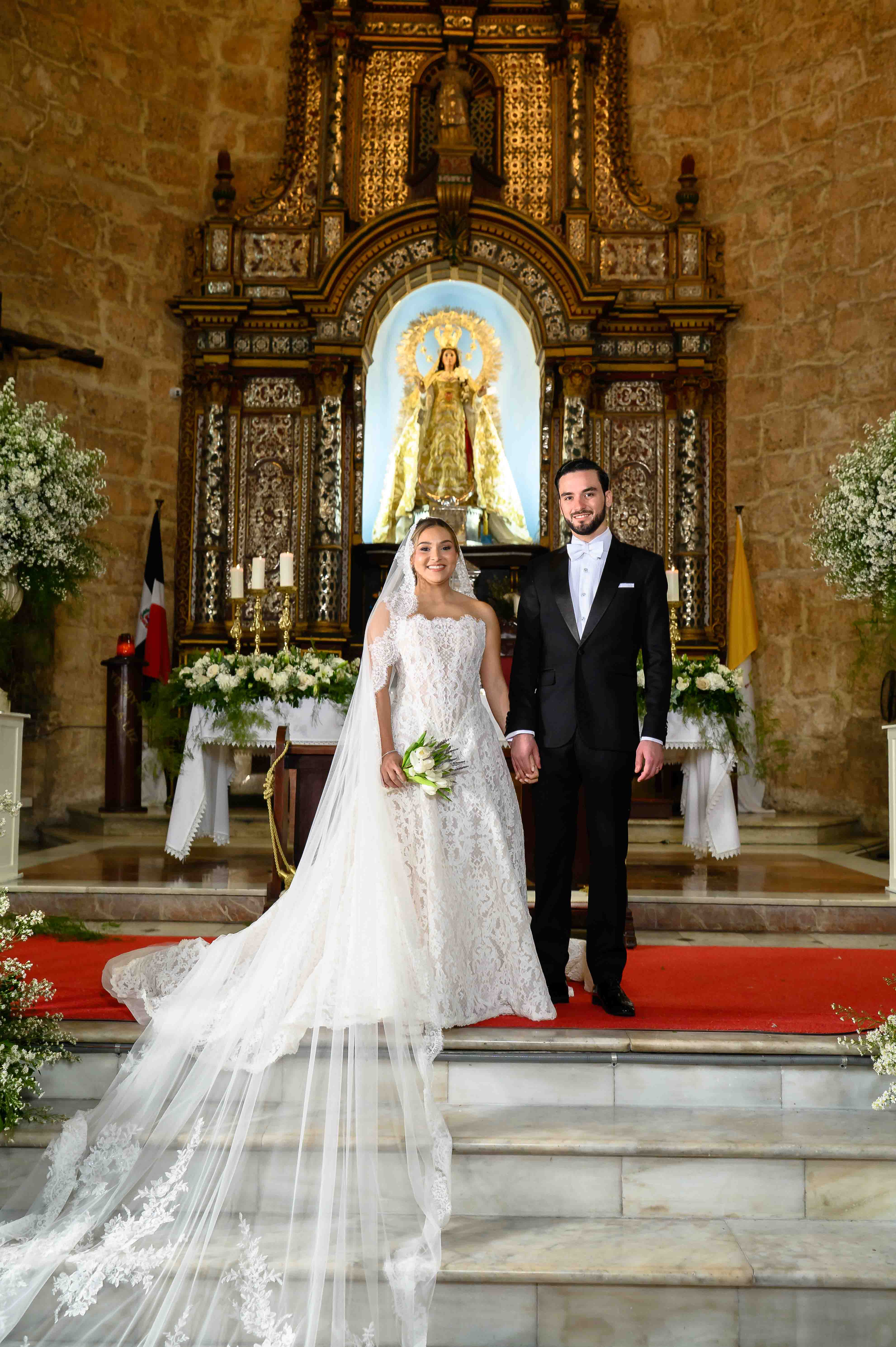 Wedding couple standing in front of an ornate altar with religious iconography.