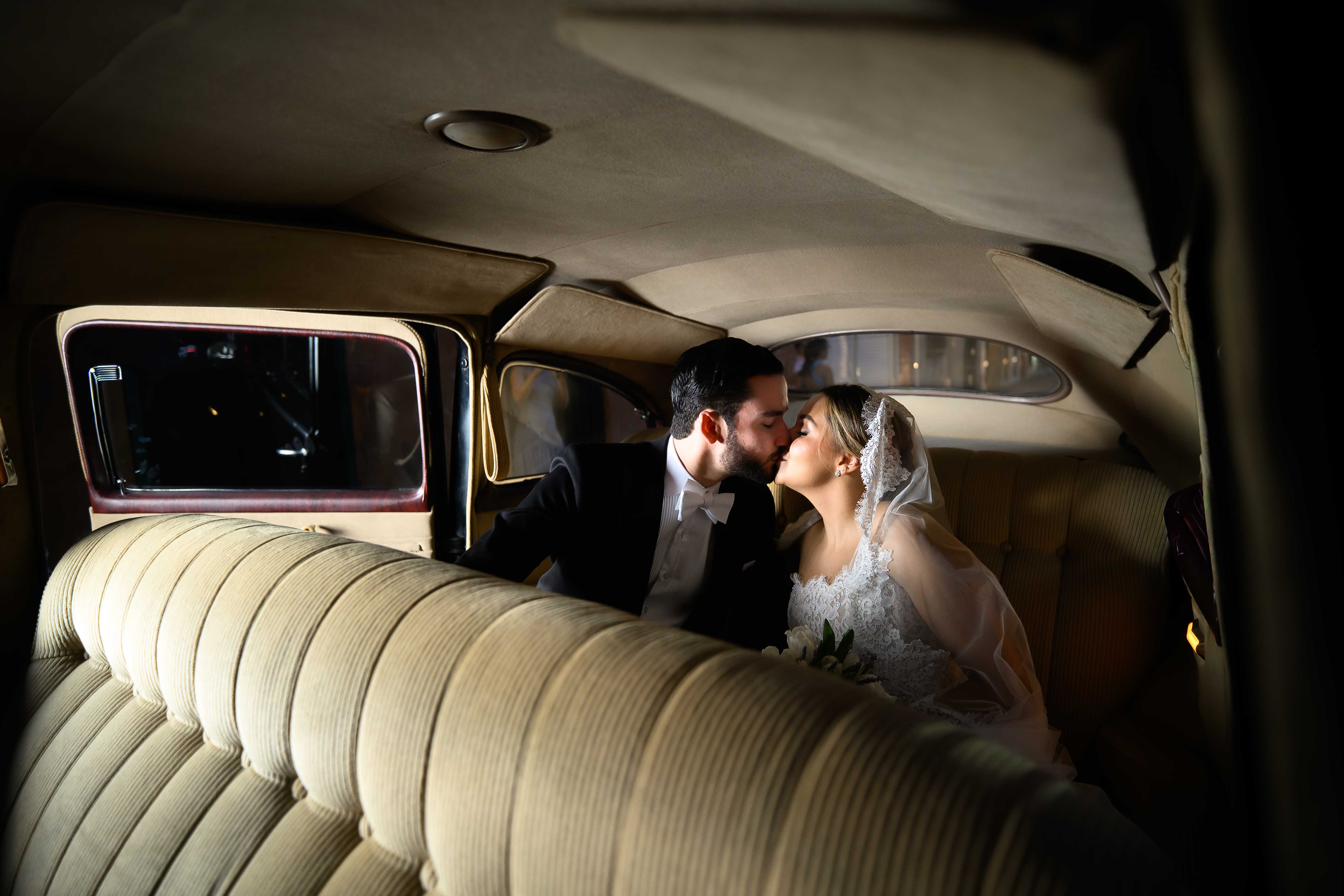 GL Bride Yamilca wearing our Splendid gown, in a vintage car on their wedding day.