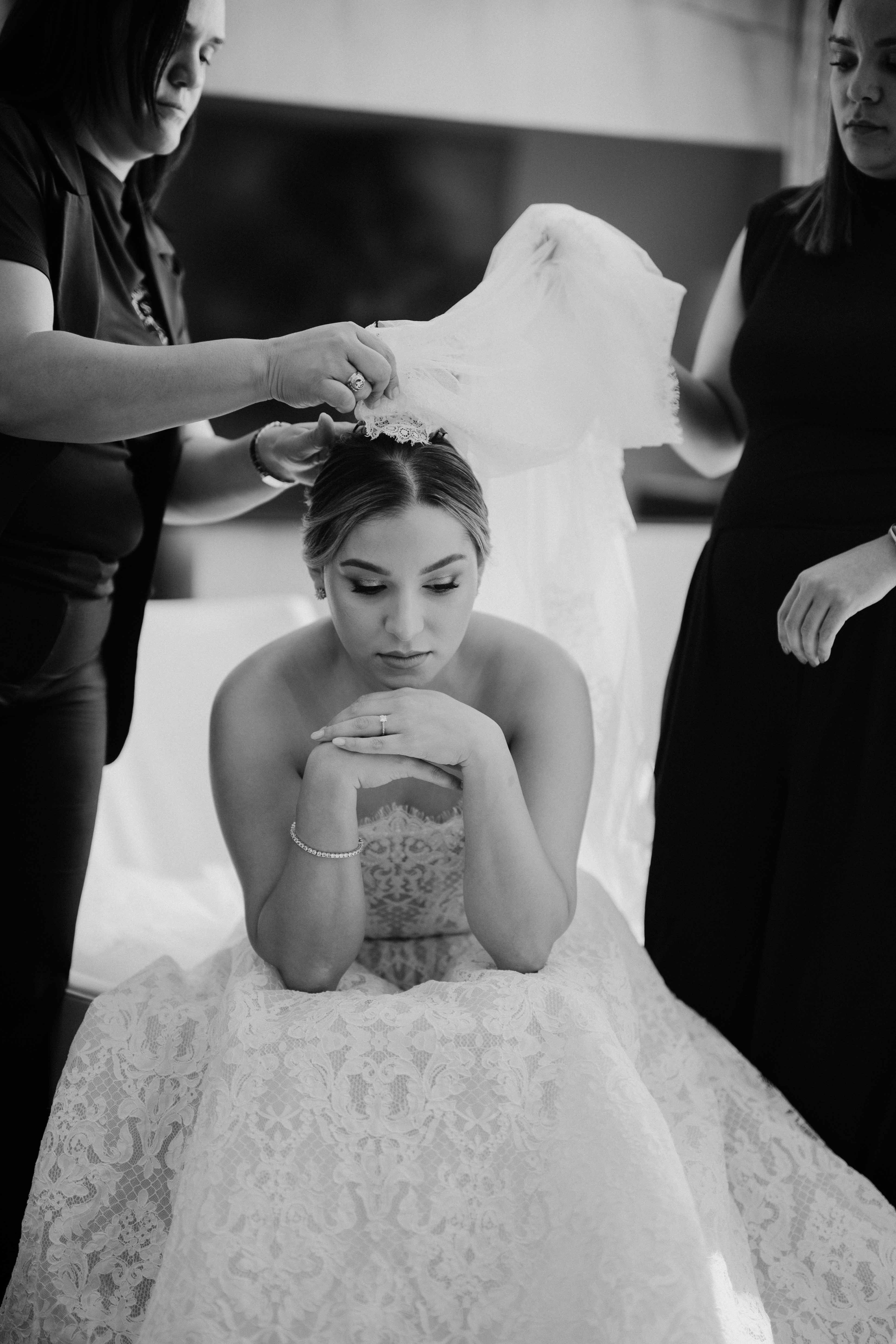 GL Bride Yamilca wearing our Splendid  being assisted by two people in a room.
