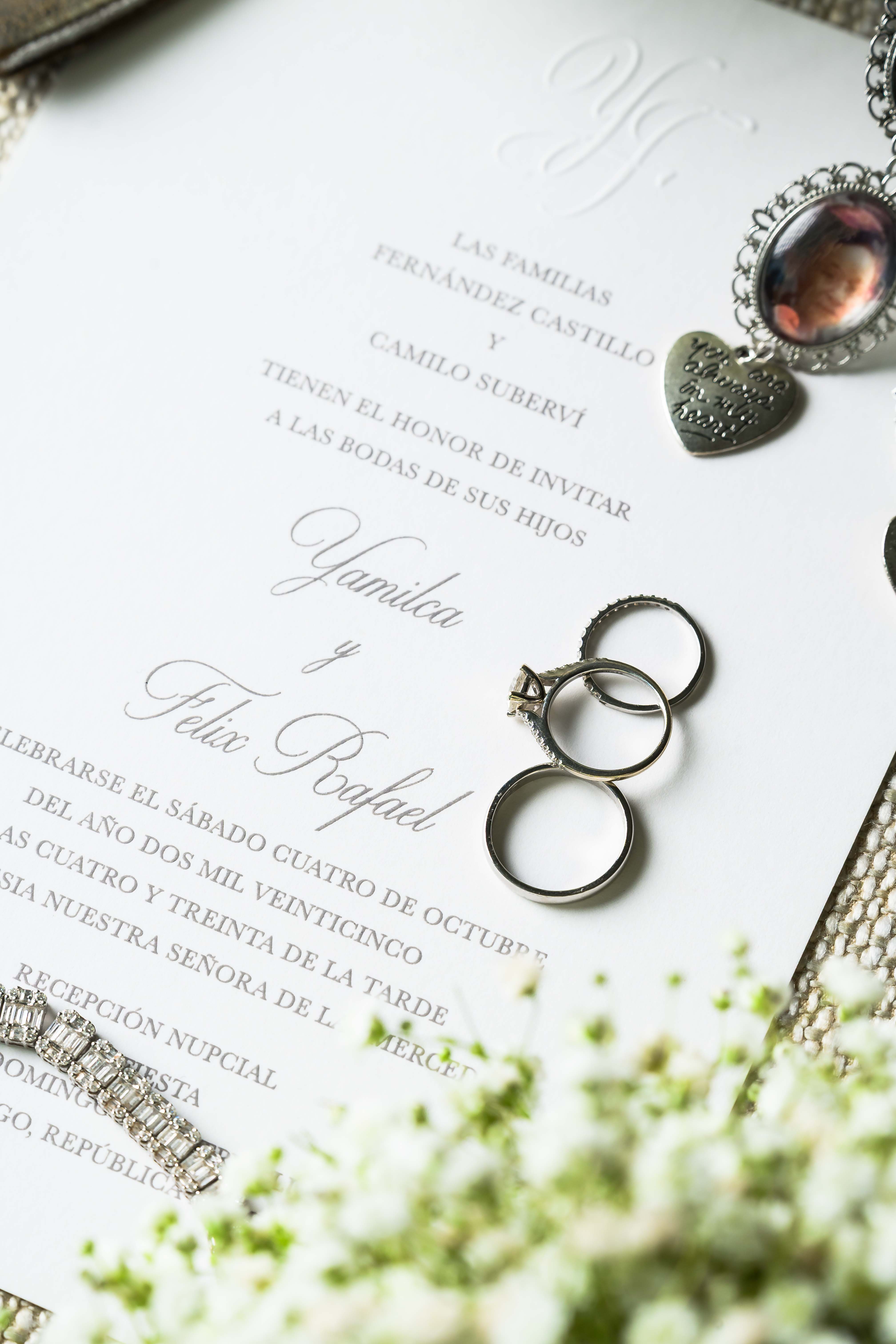 Wedding invitation with rings and jewelry on a white surface