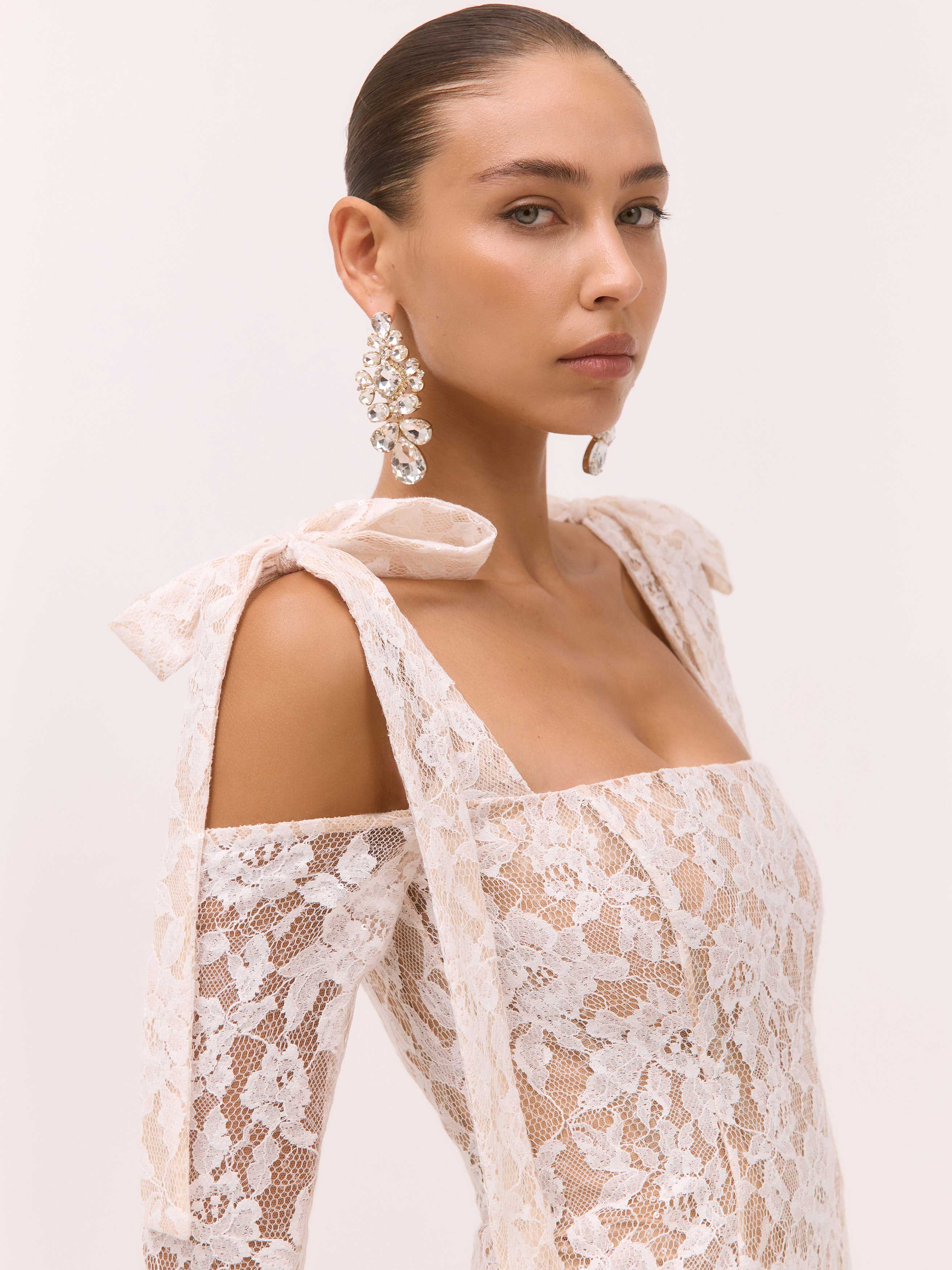 Woman wearing a white lace dress with a plain background