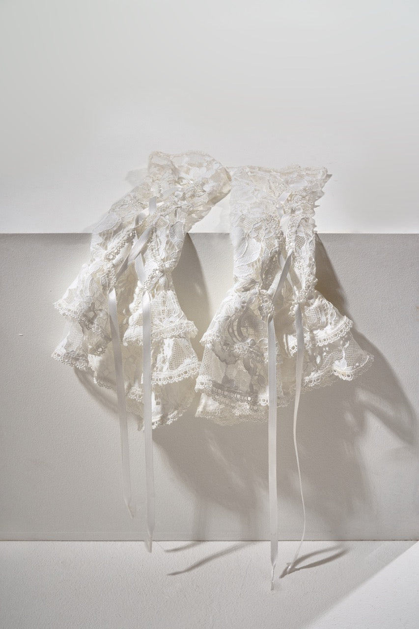 White lace fabric draped over a white surface with a soft shadow.