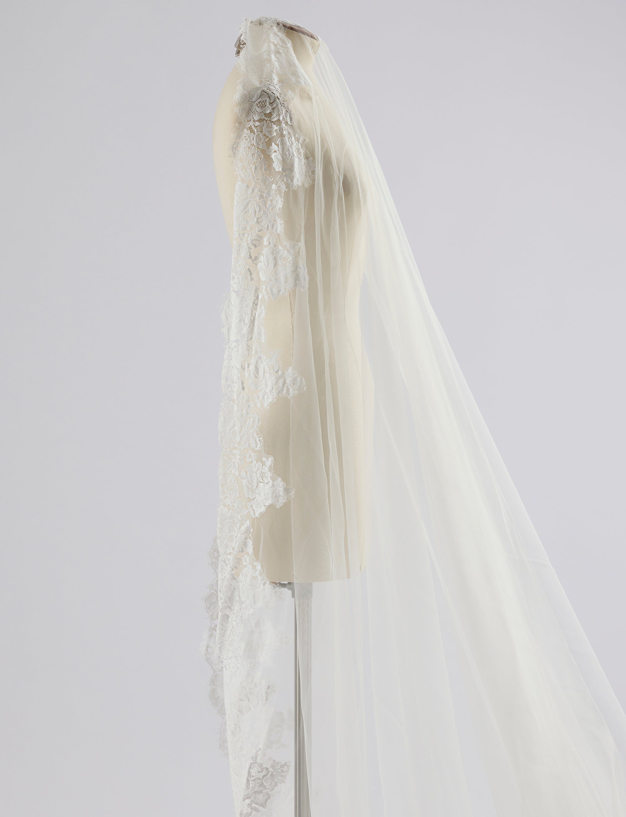 Lace wedding veil on a mannequin against a plain background