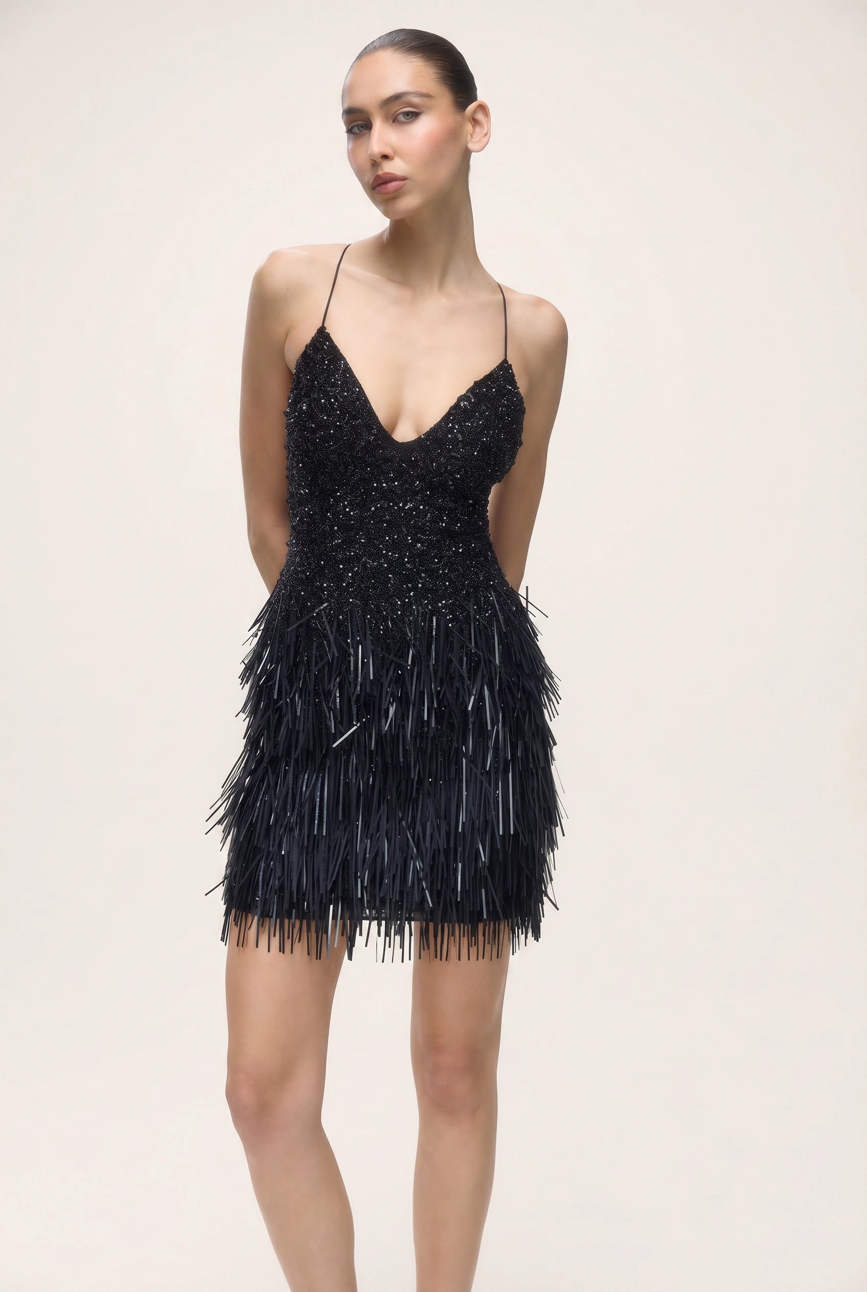 Black dress with feather details on a plain background