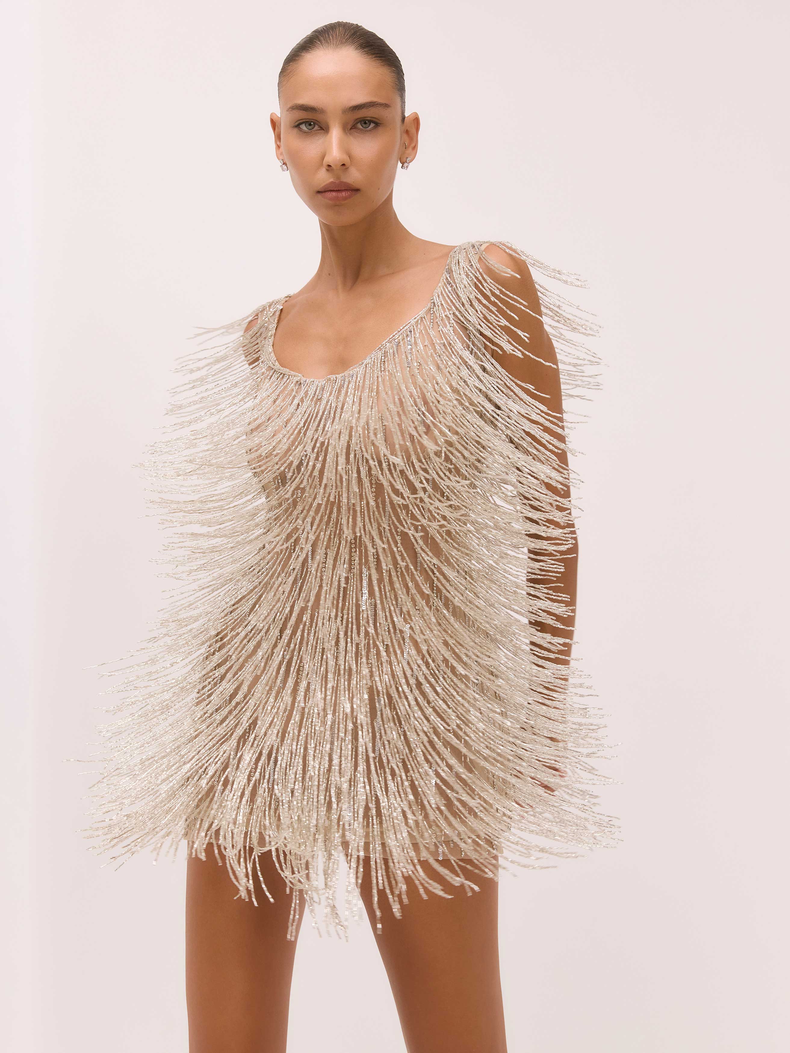 Woman wearing a beaded fringe dress on a plain background