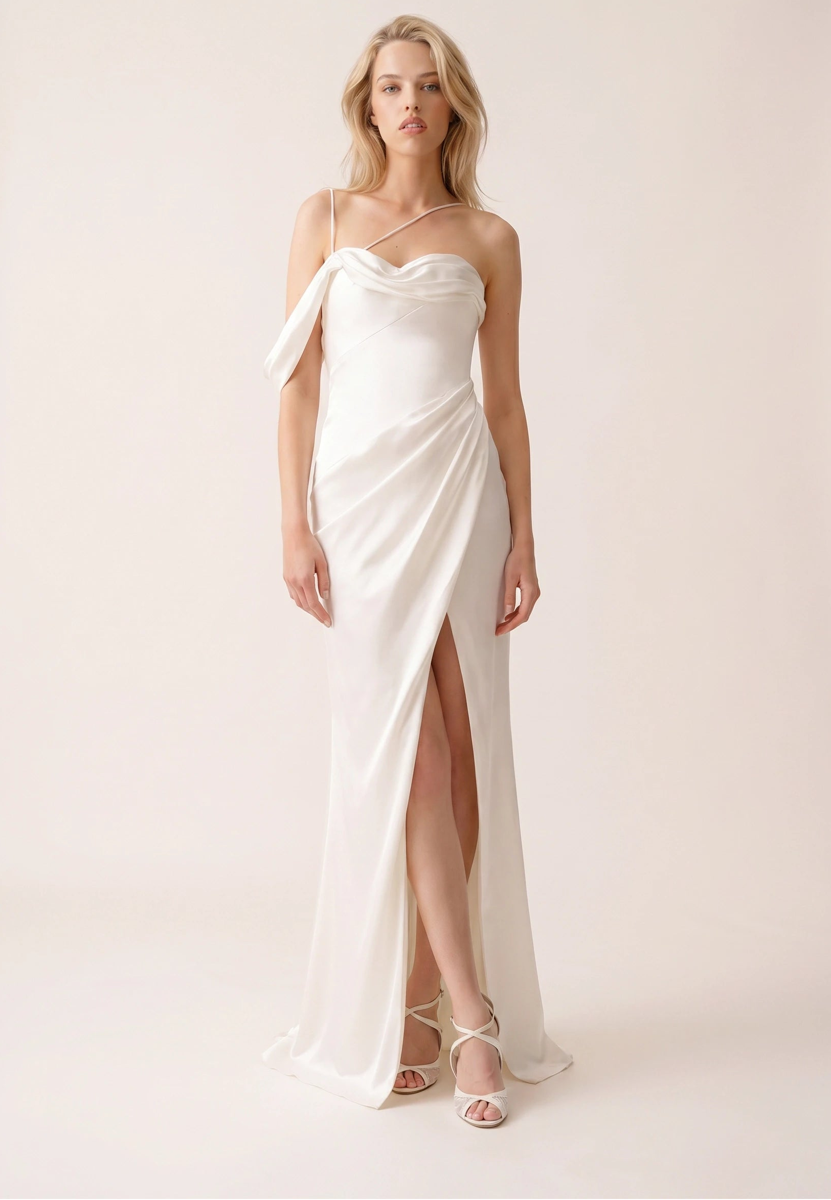 Woman wearing a white strapless gown with a high slit on a plain background