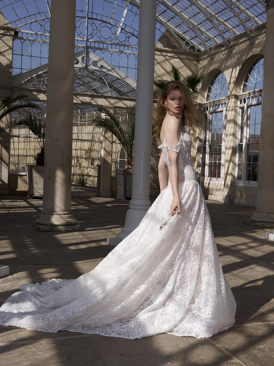 Woman in a white wedding dress standing in a conservatory.