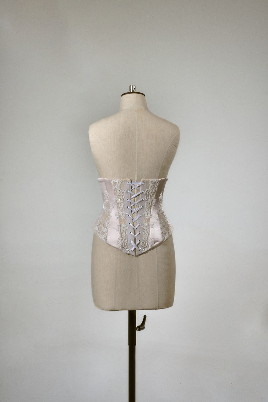 White lace corset on a mannequin against a plain background