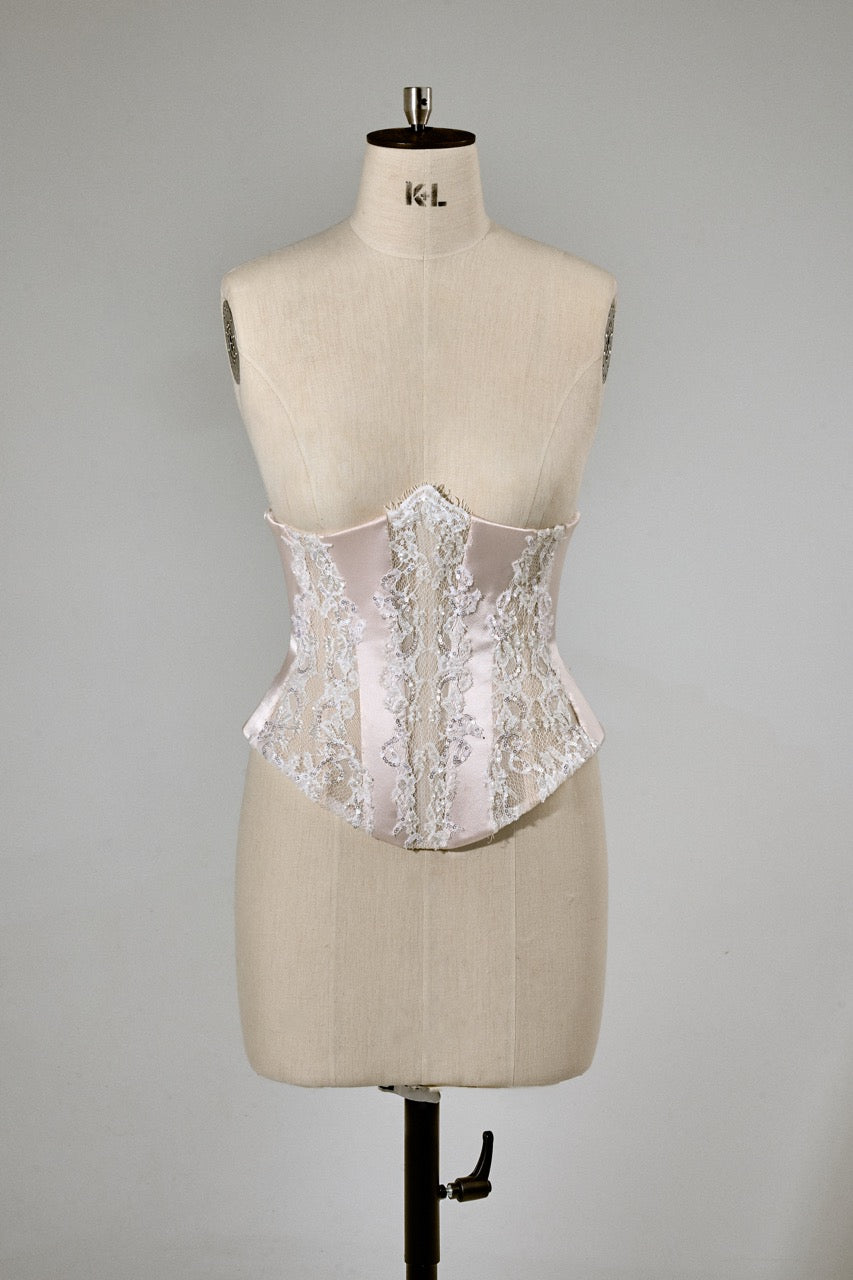 White lace corset on a mannequin against a gray background