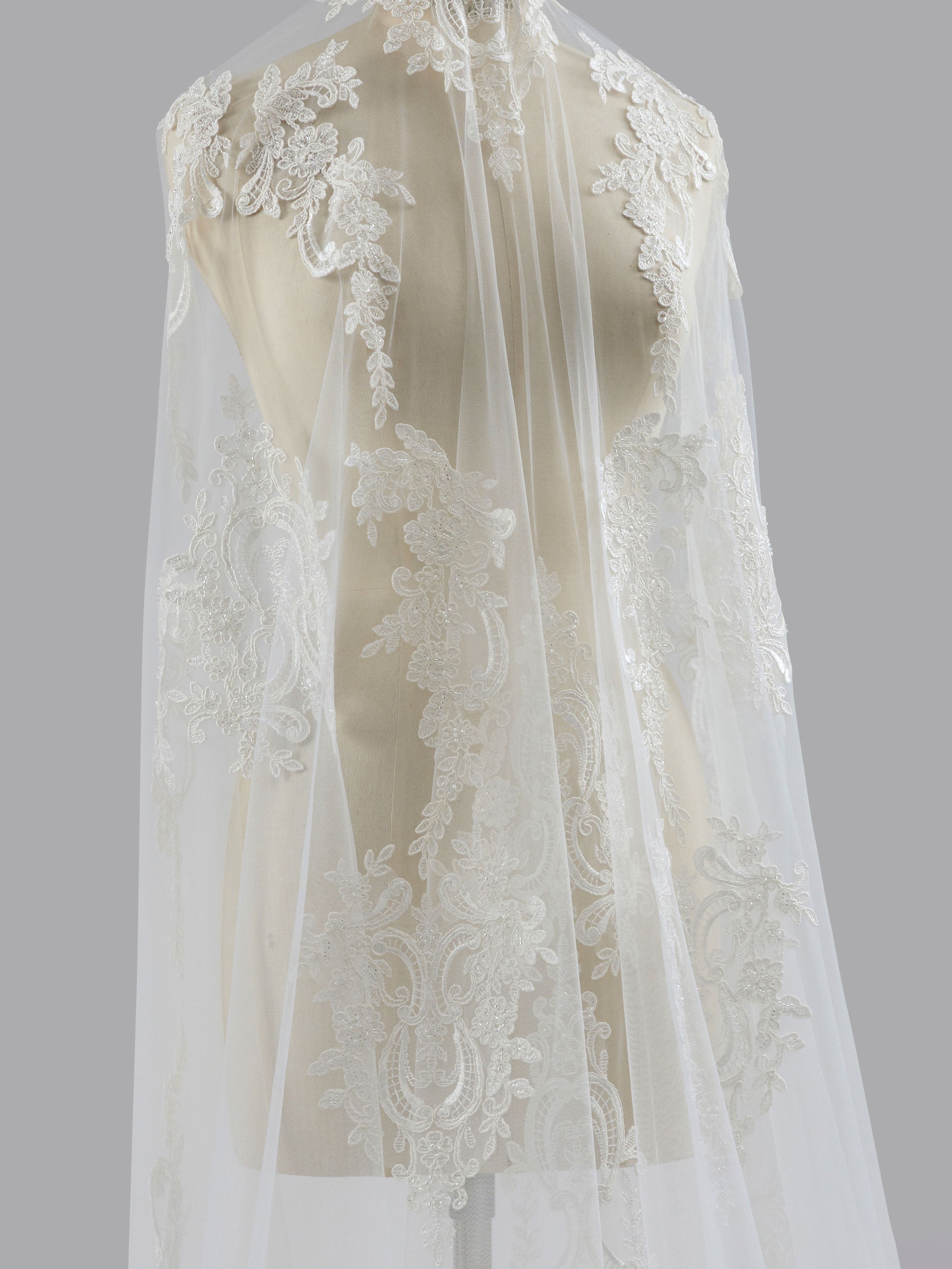 Lace wedding dress on a mannequin against a gray background