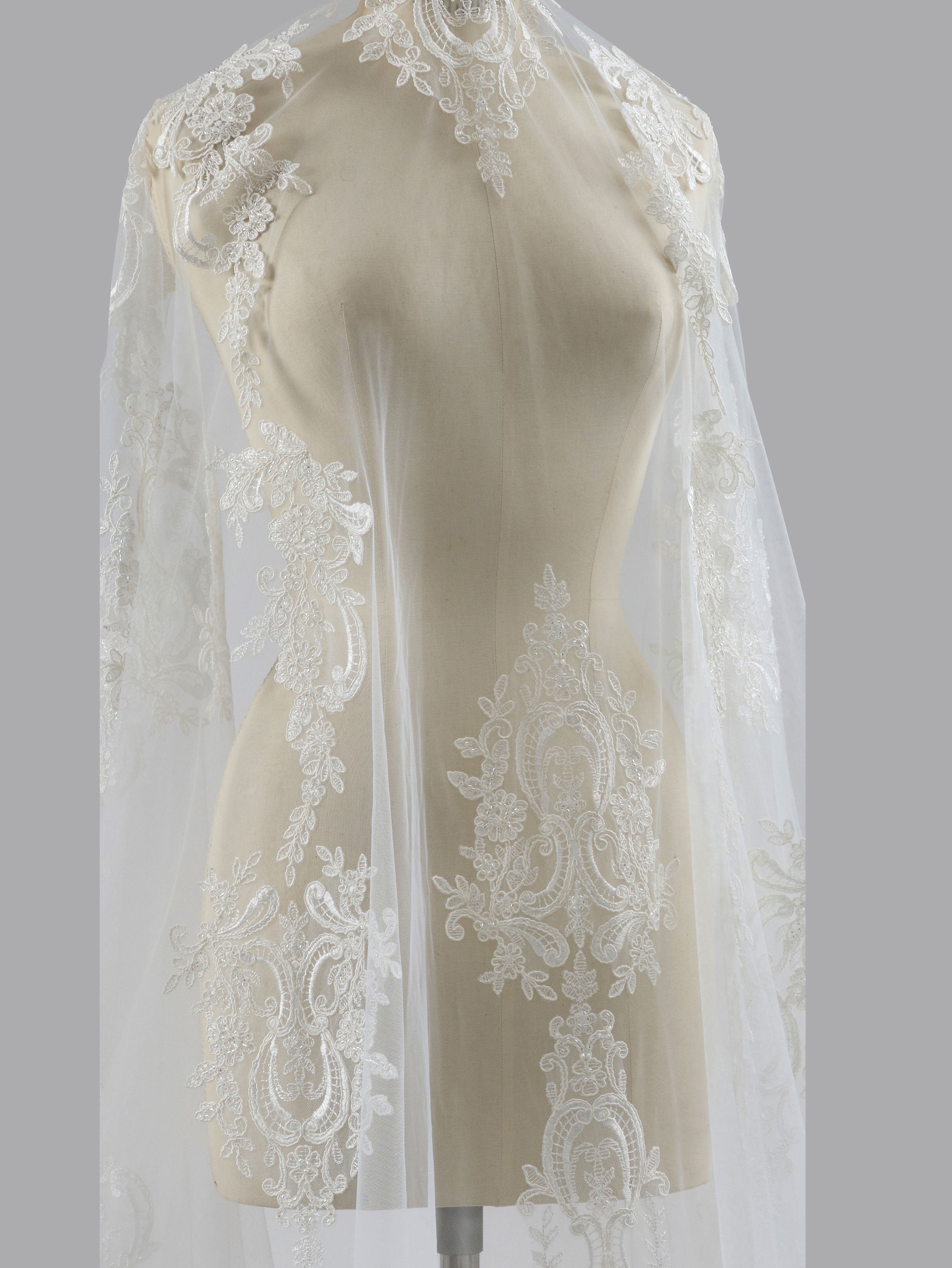 White lace veil on a mannequin against a gray background