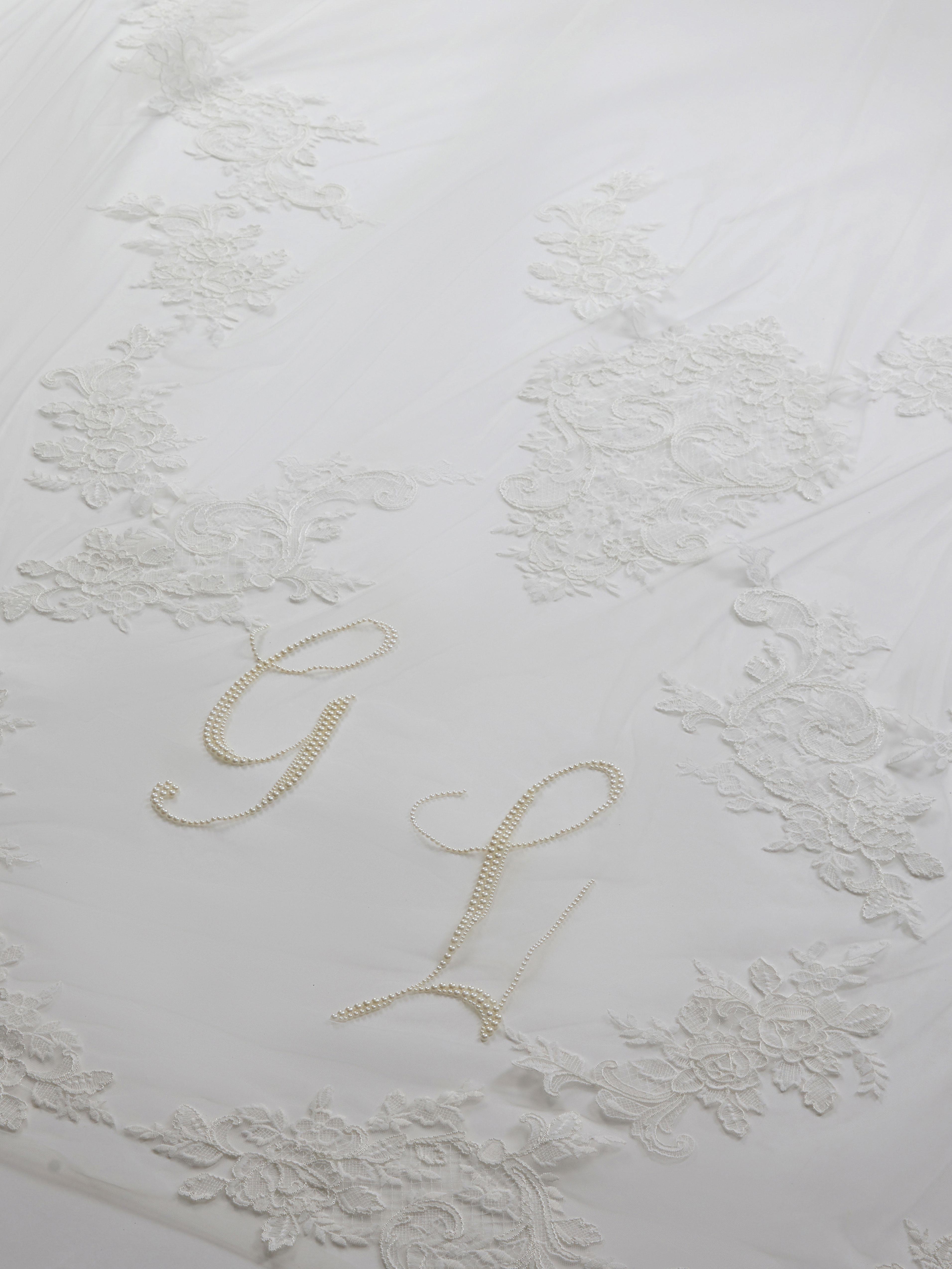 Decorative white pillow with embroidered initials on a textured white background